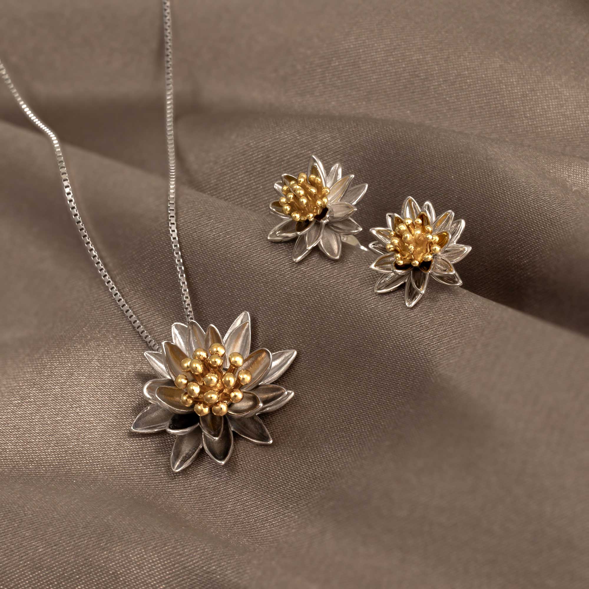 Sterling silver earrings designed as water lily flowers with layered petals and gold-toned bead clusters at the center, showcasing intricate British craftsmanship.