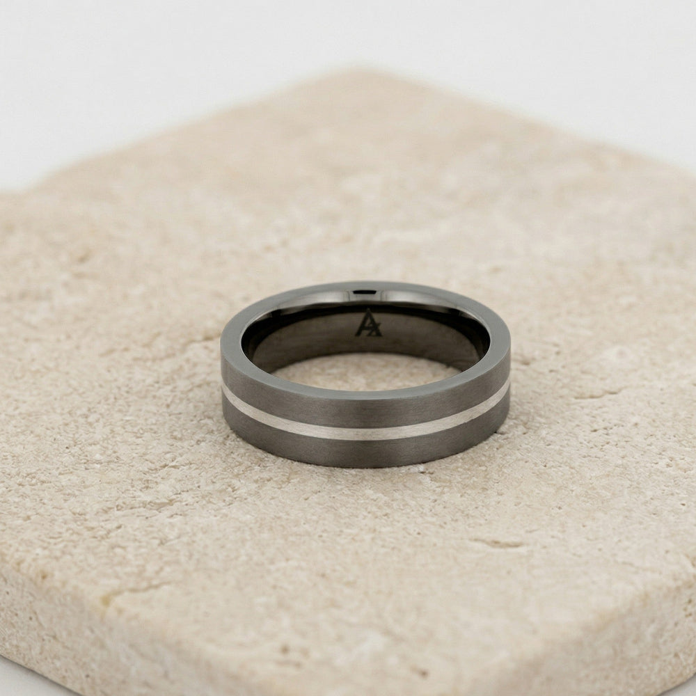 Contemporary titanium ring featuring a central sterling silver stripe, showcasing a sleek and sculptural design from a British jewellery brand.