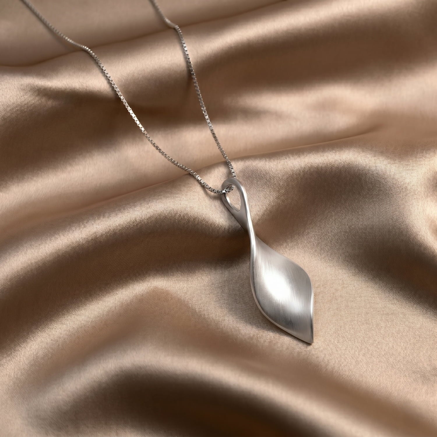 Silver twisting pendant on a beige fabric background