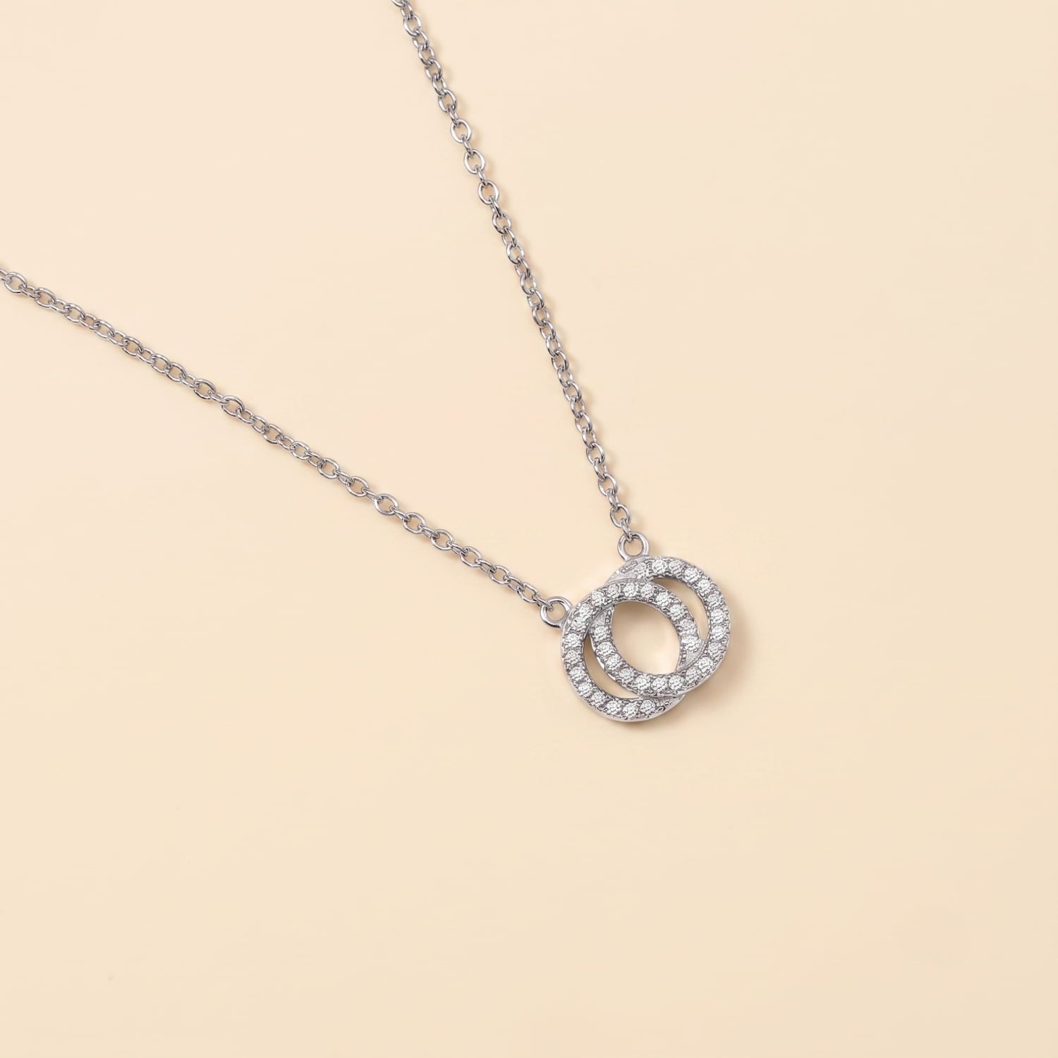 Delicate sterling silver necklace featuring two interlocking circles embellished with sparkling white topaz stones, designed for adjustable length and refined elegance.