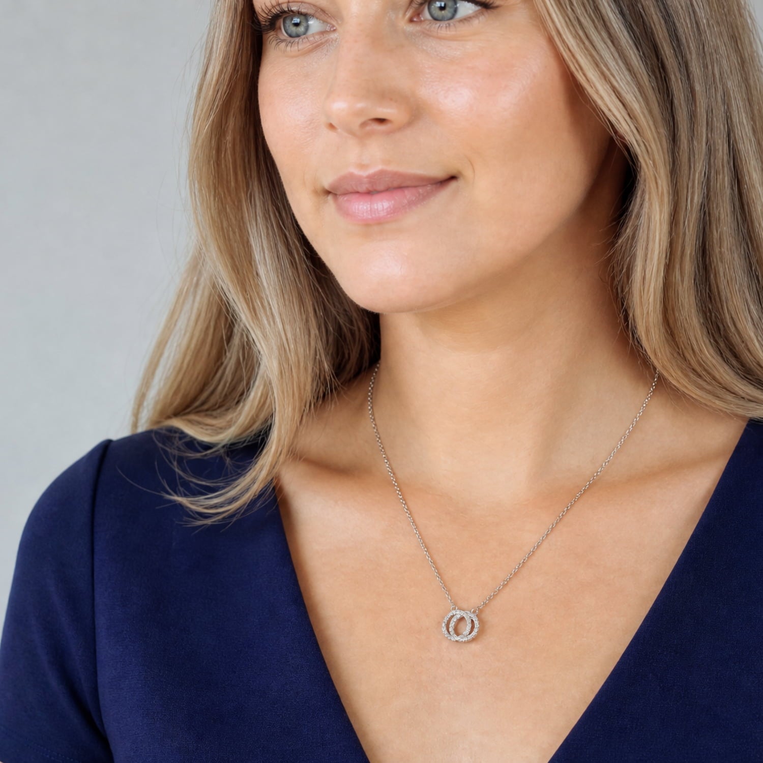 Delicate sterling silver necklace featuring two reversible interlocking circles with a subtle textured finish on a fine adjustable chain for versatile layering.