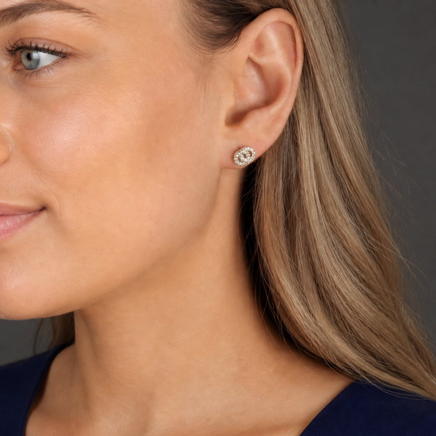 Close-up of an ear adorned with sterling silver stud earrings featuring interlocking circles set with sparkling cubic zirconia, showcasing a modern and elegant silver jewellery design.