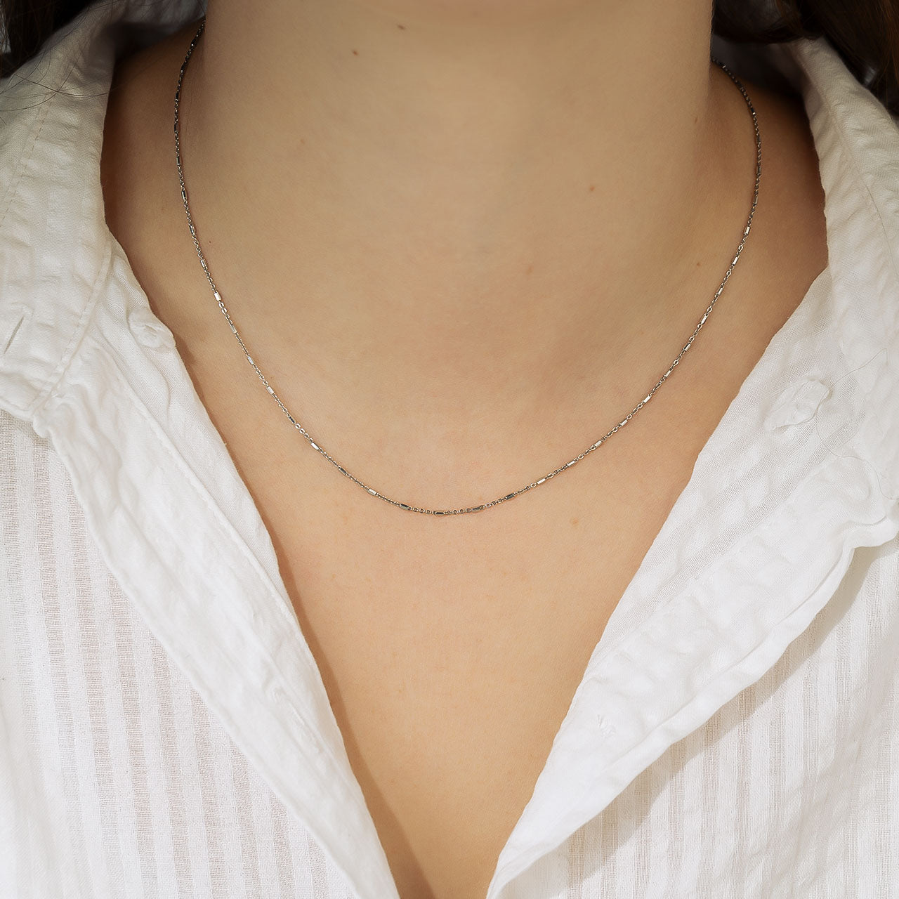 Delicate sterling silver necklace featuring a fine chain interspersed with small cube-shaped links, exemplifying minimalist contemporary sterling silver jewellery design.