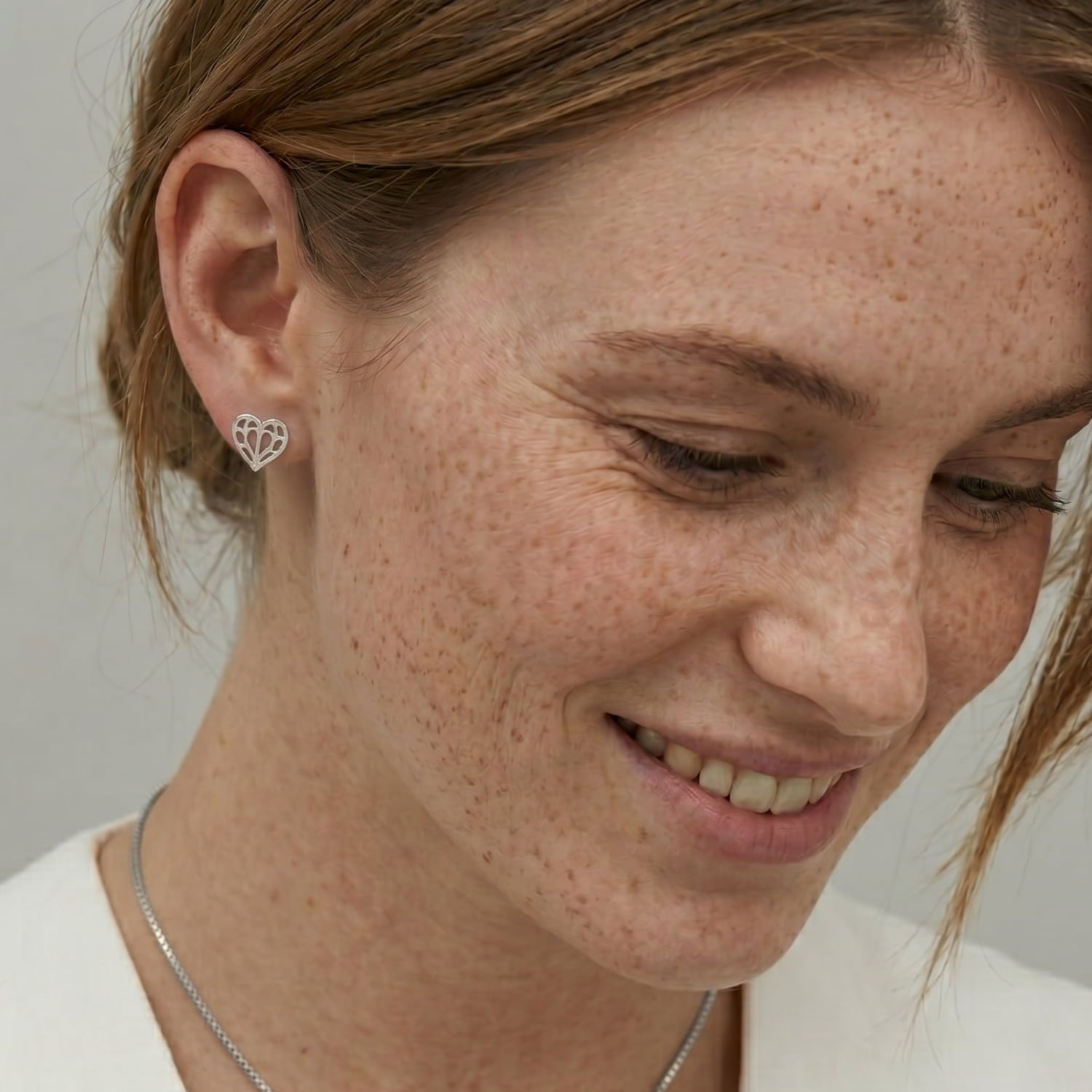 Close-up of a sterling silver stud earring shaped as an openwork heart inspired by Yorkshire, worn on an ear, showcasing delicate and sculptural silver jewellery design.