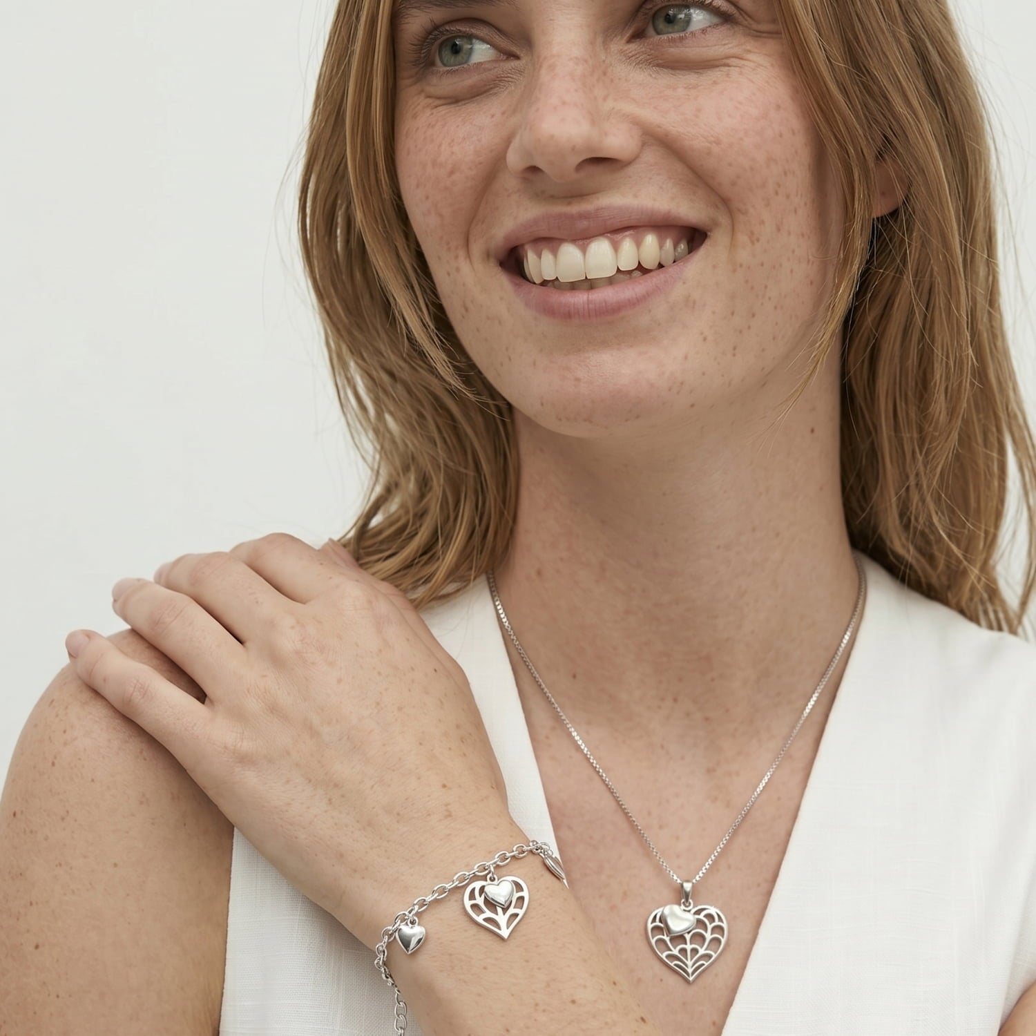 Sterling silver bracelet with a sculptural chain and an openwork heart charm, displayed on a wrist, showcasing refined silver jewellery design.