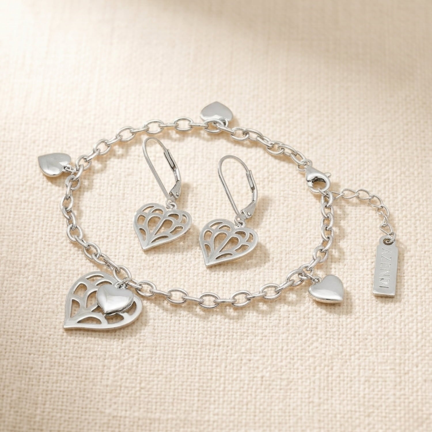 Sterling silver jewellery set featuring an intricate heart bracelet with an adjustable chain featuring four polished heart charms and a larger openwork heart charm and matching earrings, showcasing sculptural Yorkshire-inspired design.