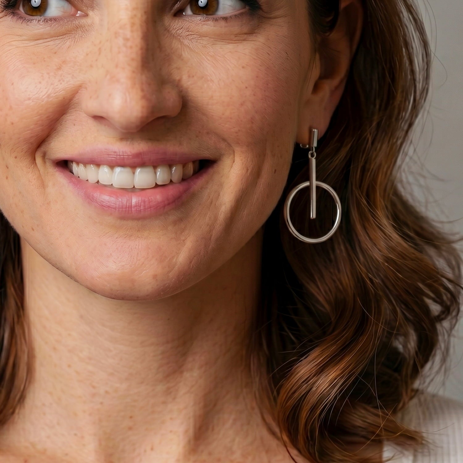 Close-up of a woman wearing circle and line drop earrings