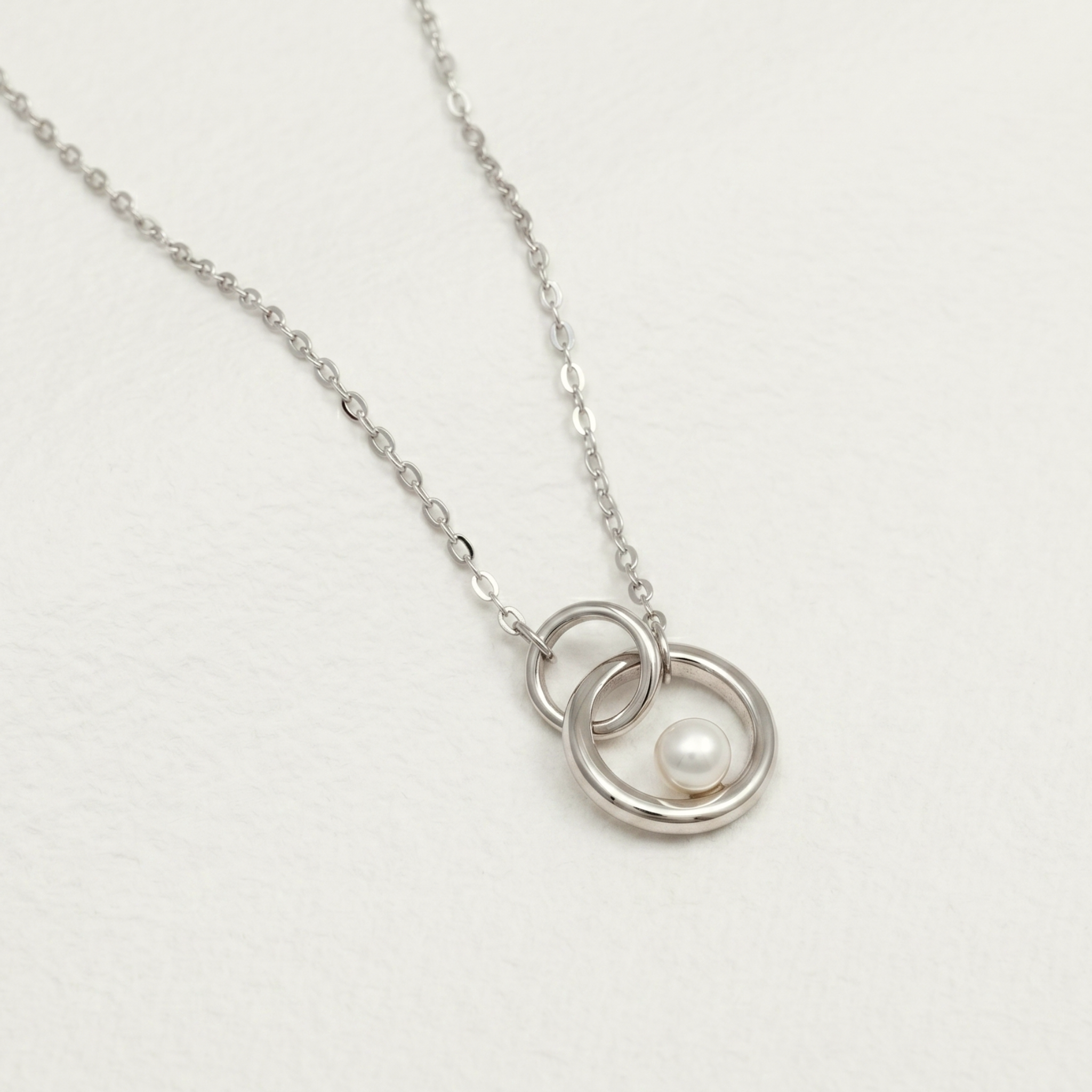 A sterling silver necklace with interlocking circle pendants and a freshwater pearl centerpiece.