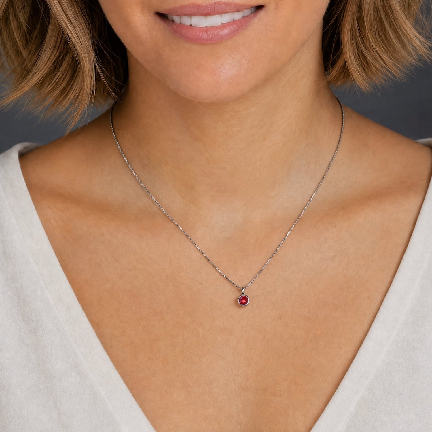 Sterling silver necklace featuring a sculptural garnet pendant with a faceted deep red gemstone, showcasing expert British craftsmanship