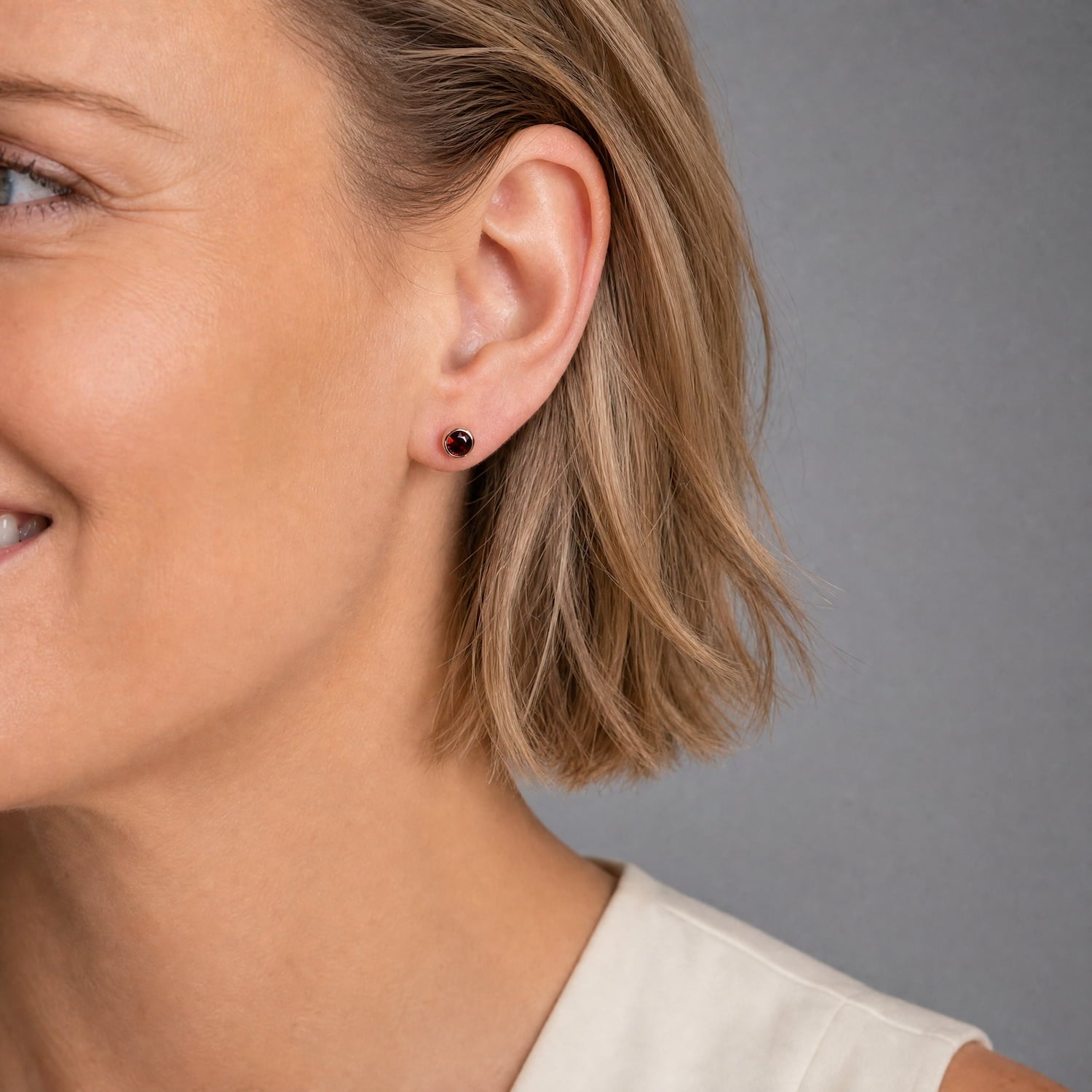 Delicate sterling silver stud earrings featuring deep red garnet January birthstones, showcasing a refined and timeless design by an award-winning British jeweller.