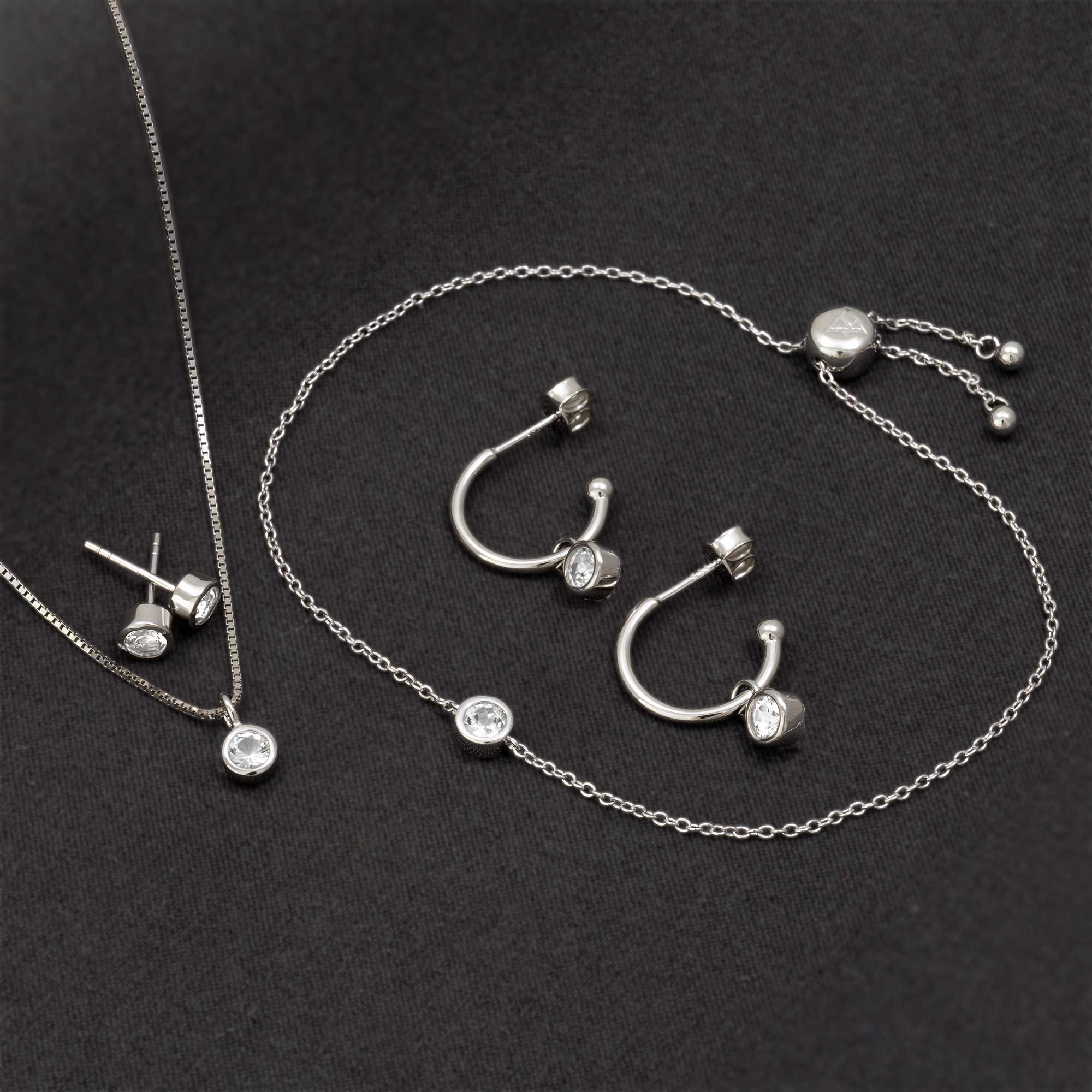 Delicate sterling silver hoop earrings and necklace featuring sparkling white topaz stones, highlighting contemporary sculptural design with expert British craftsmanship.