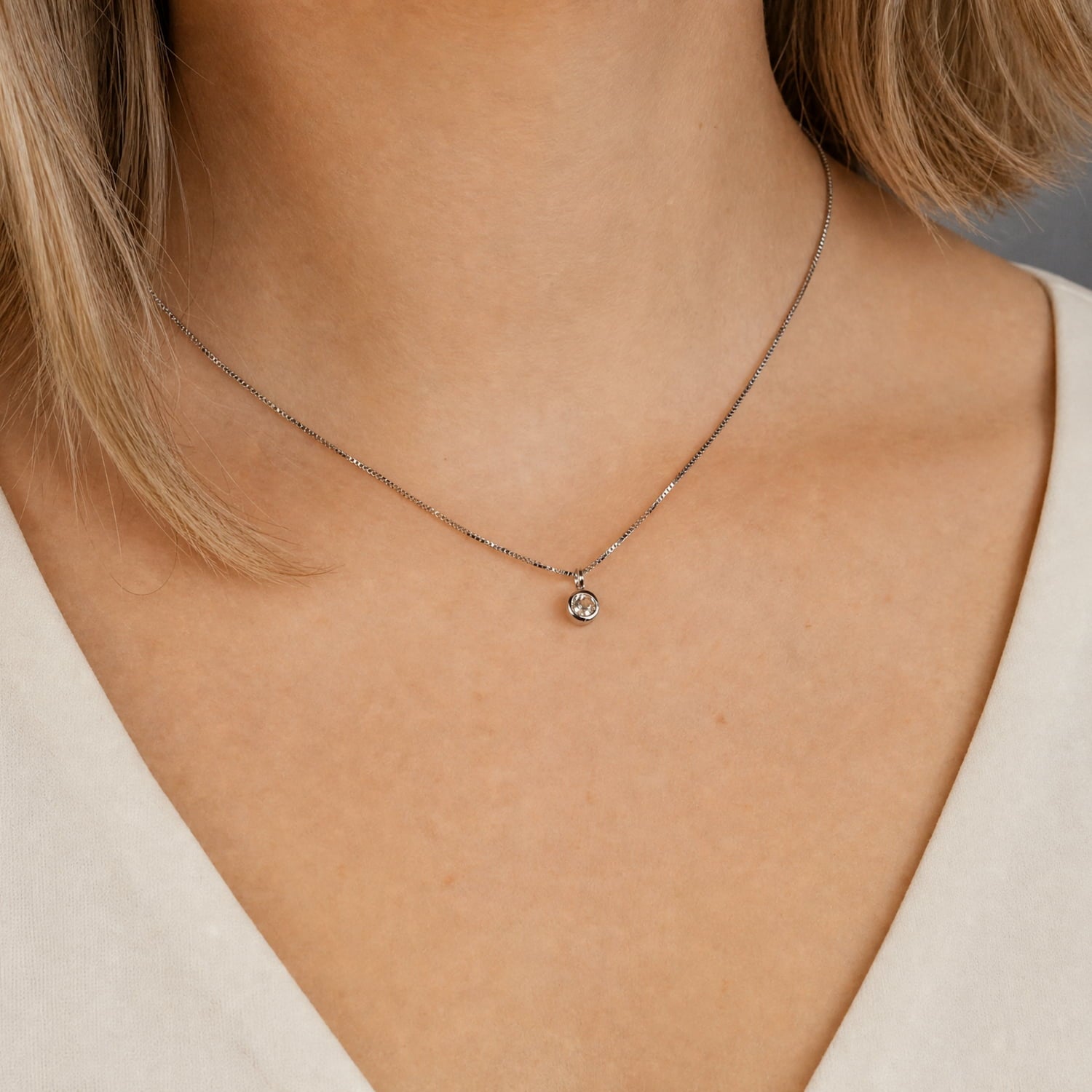 Elegant sterling silver pendant featuring a white topaz gemstone on a fine chain, worn with a soft cream blouse for a sophisticated and timeless look.