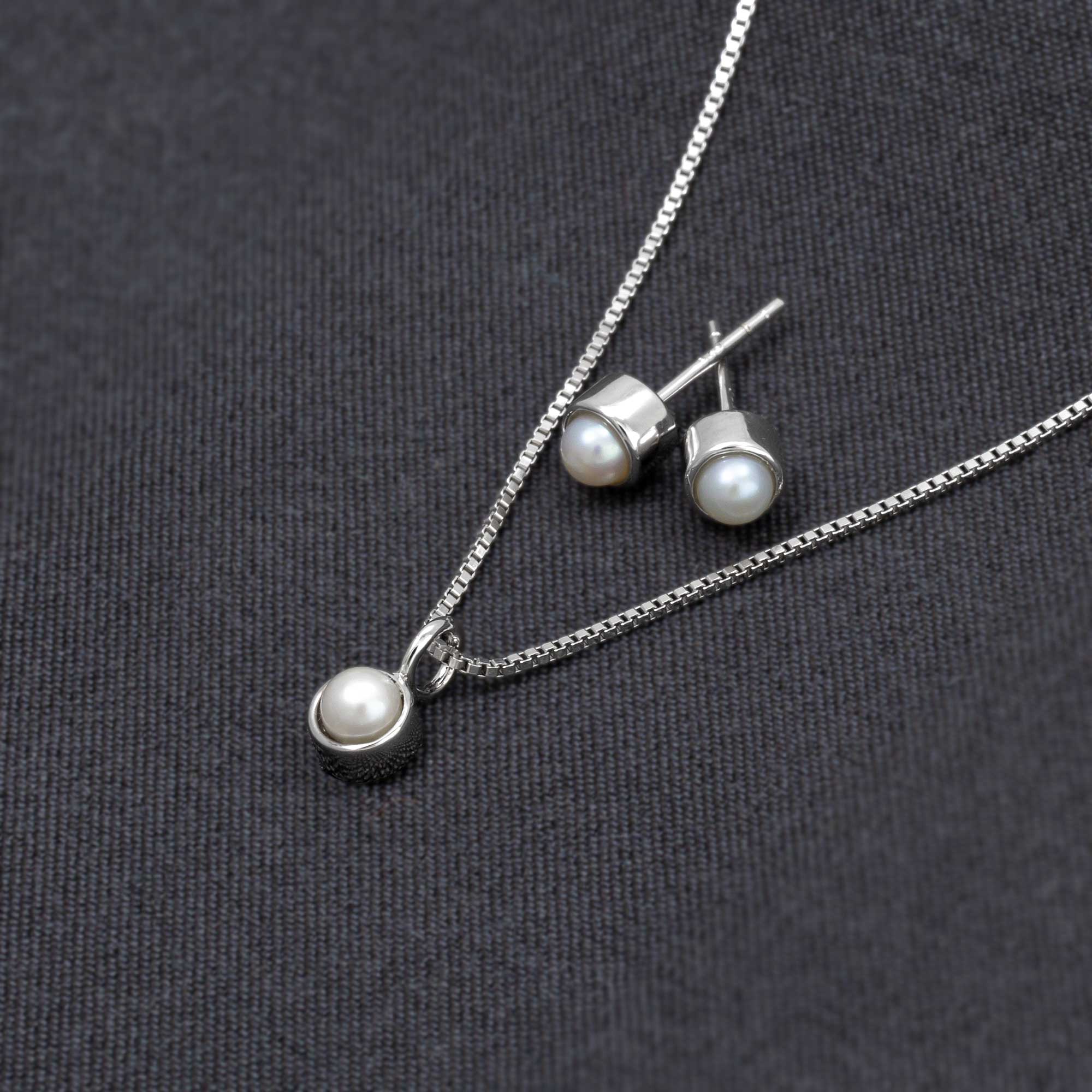 Delicate sterling silver earrings with freshwater pearls, paired with a matching pendant on a fine chain, showcasing expert British craftsmanship with a minimalist design.