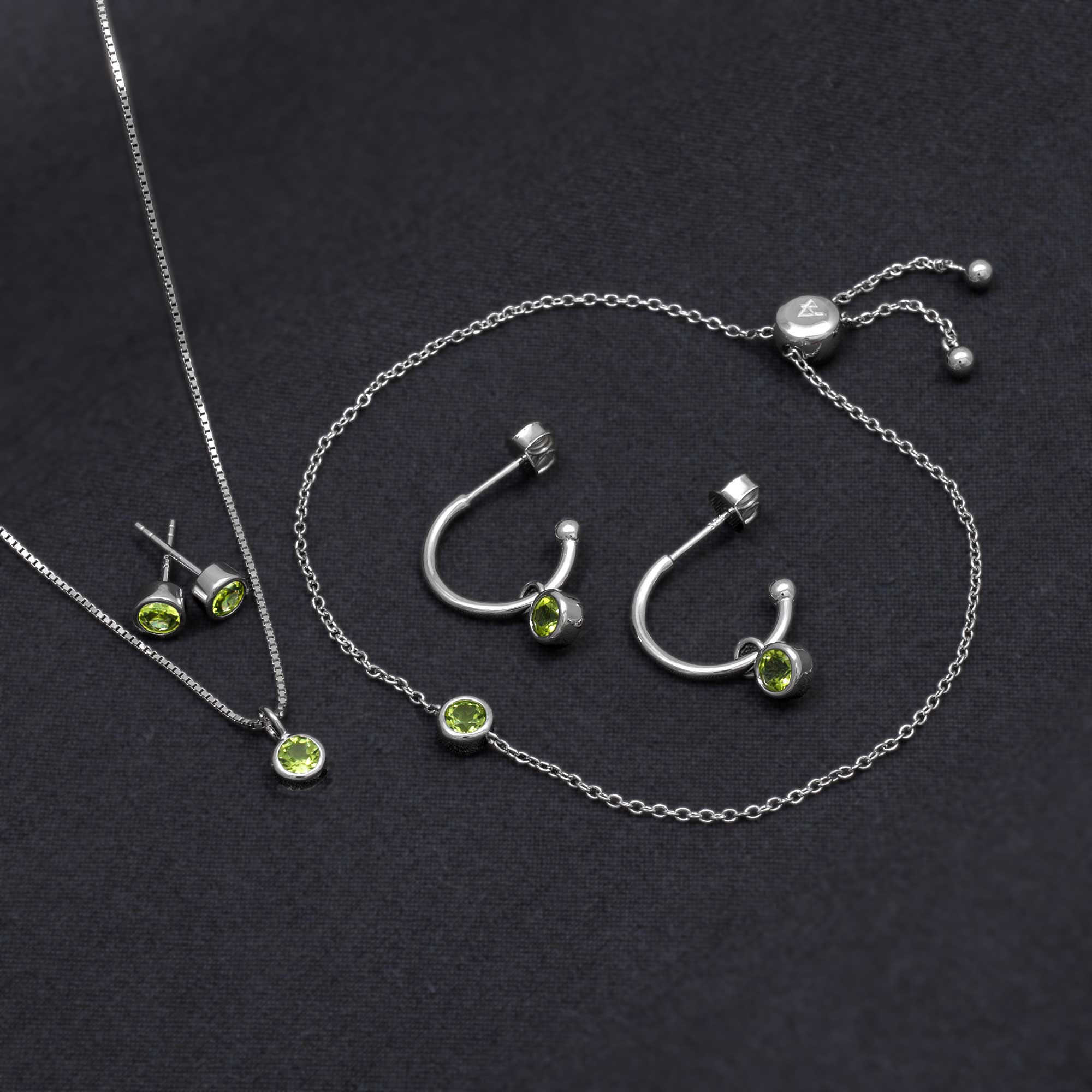 Sterling silver jewellery set featuring peridot gemstones, including hoop earrings, studs, a pendant, and a delicate adjustable bracelet, showcasing expert British craftsmanship.