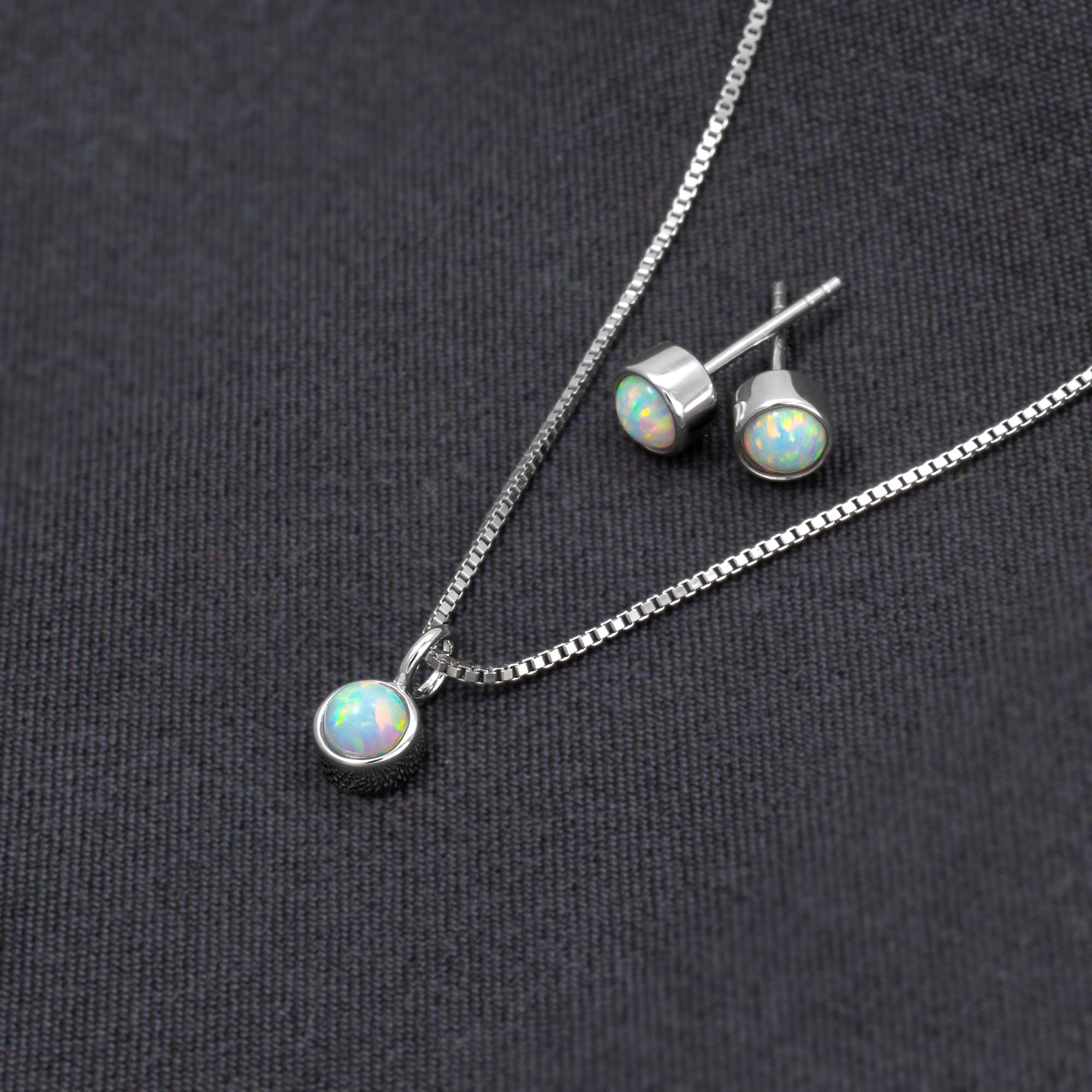 Delicate sterling silver stud earrings featuring luminous opal gemstones, paired with a matching pendant on a fine chain, exemplifying expert British craftsmanship.