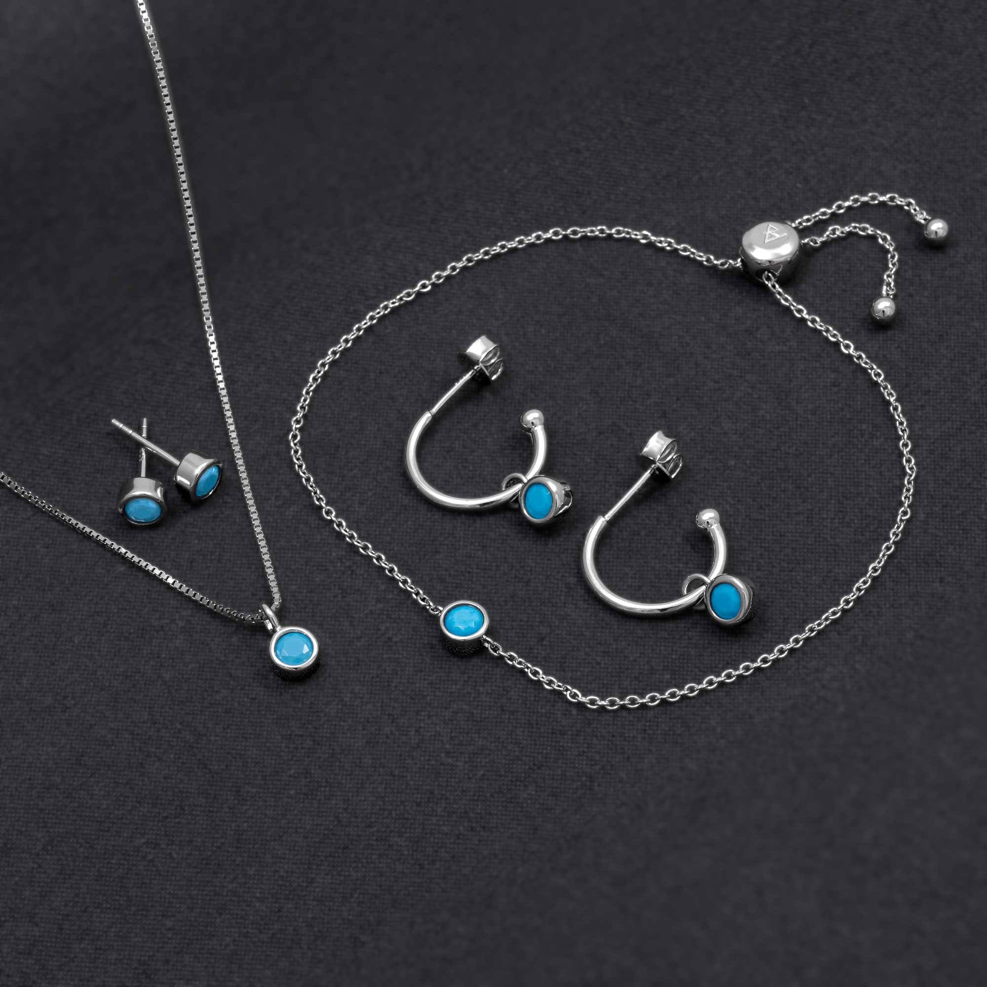 Delicate sterling silver jewellery set featuring turquoise December birthstones in polished round settings, including hoop earrings, stud earrings, a necklace, and an adjustable bracelet.