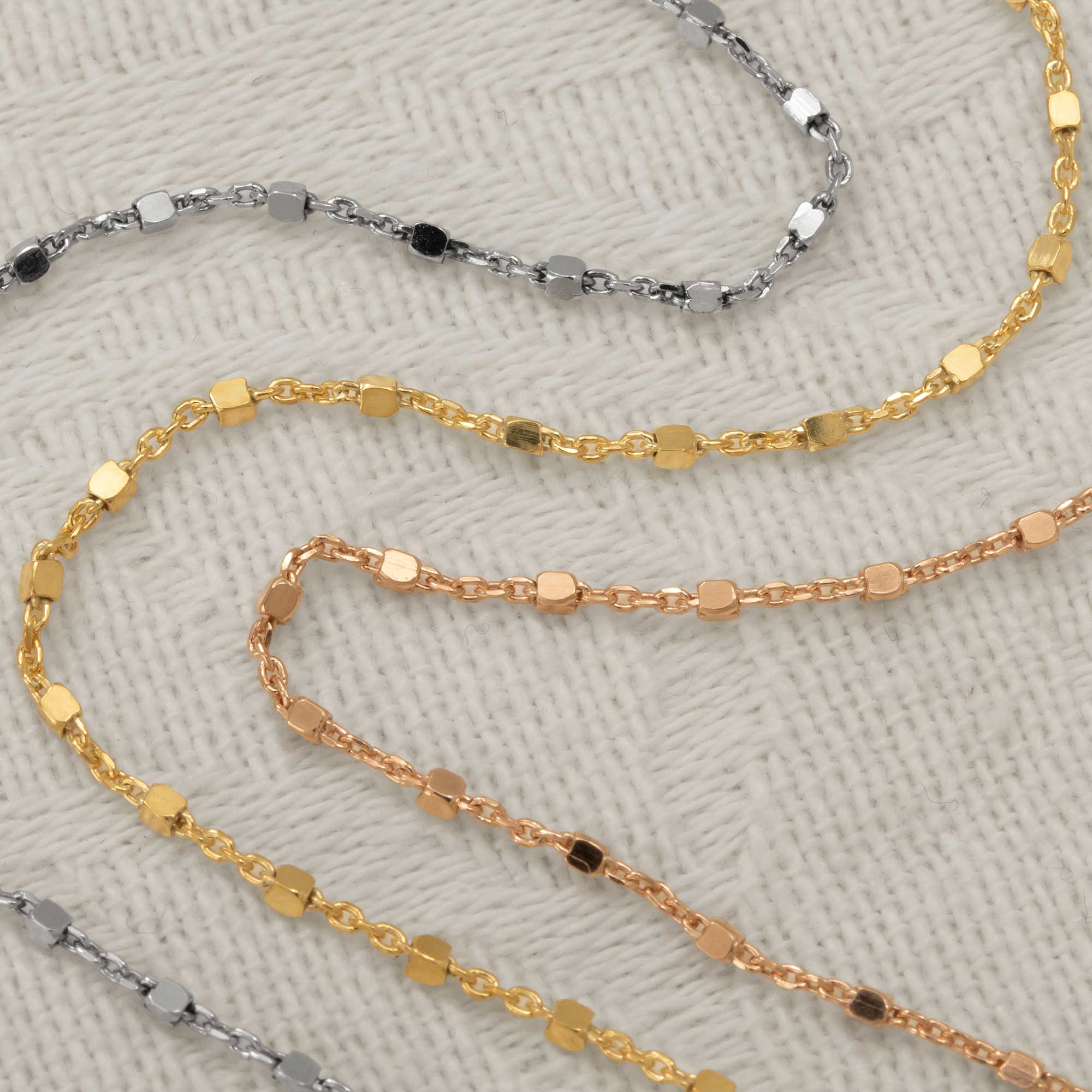 Delicate silver chains featuring small sculptural cube links in multiple finishes, showcasing a modern and refined design ideal for contemporary silver jewellery collections.