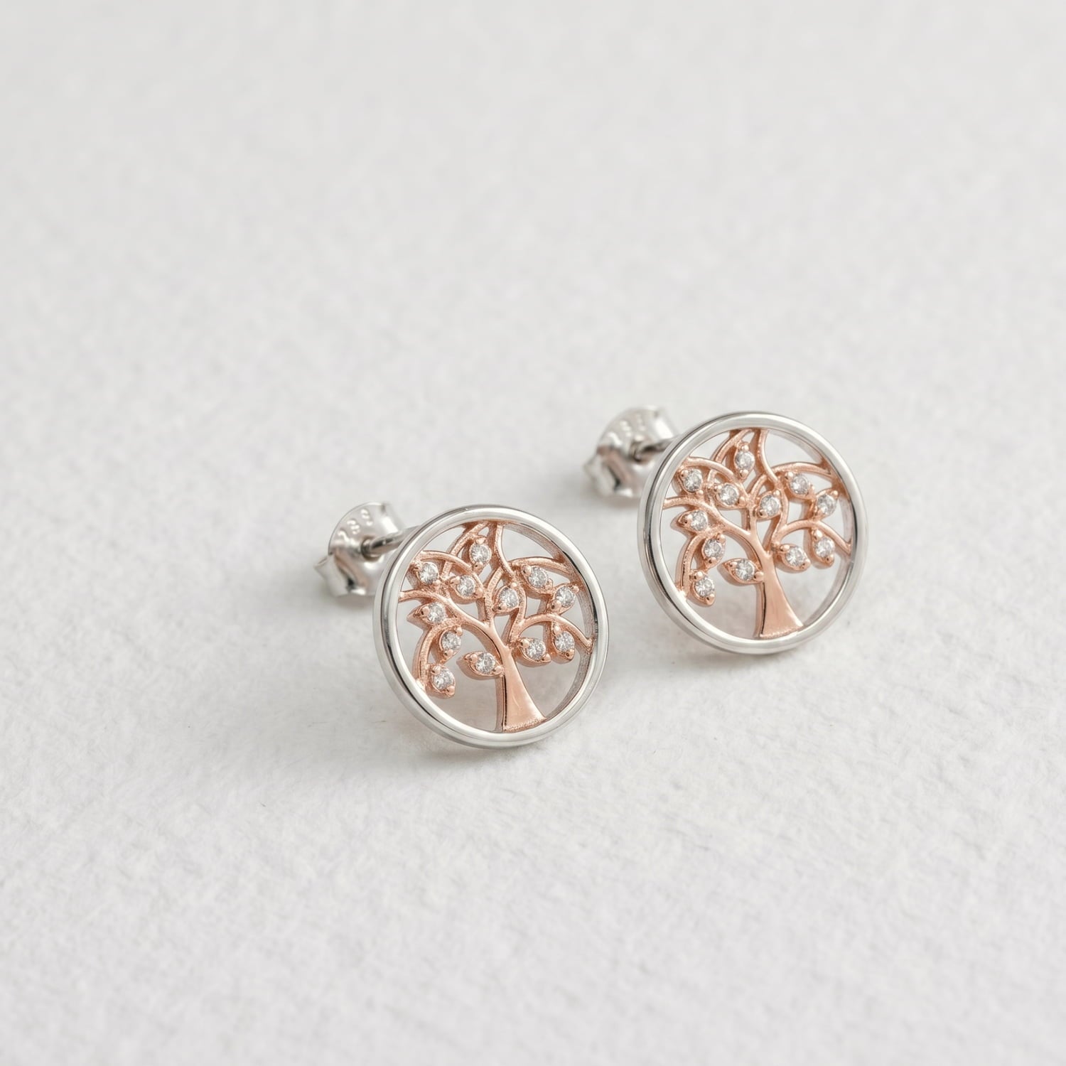 Pair of sterling silver stud earrings featuring a sculptural tree motif in rose gold with delicate gemstone accents, showcasing refined contemporary silver jewellery design.