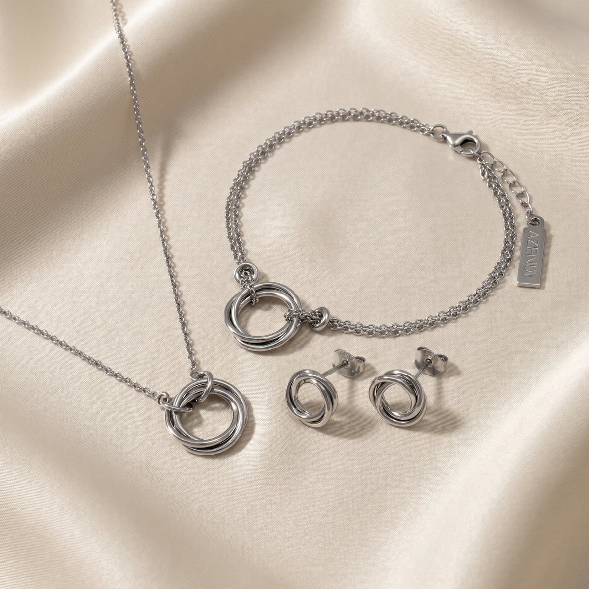 Sterling silver necklace, bracelet, and stud earrings featuring intertwined knot and circular designs, showcasing sculptural elegance in contemporary silver jewellery.