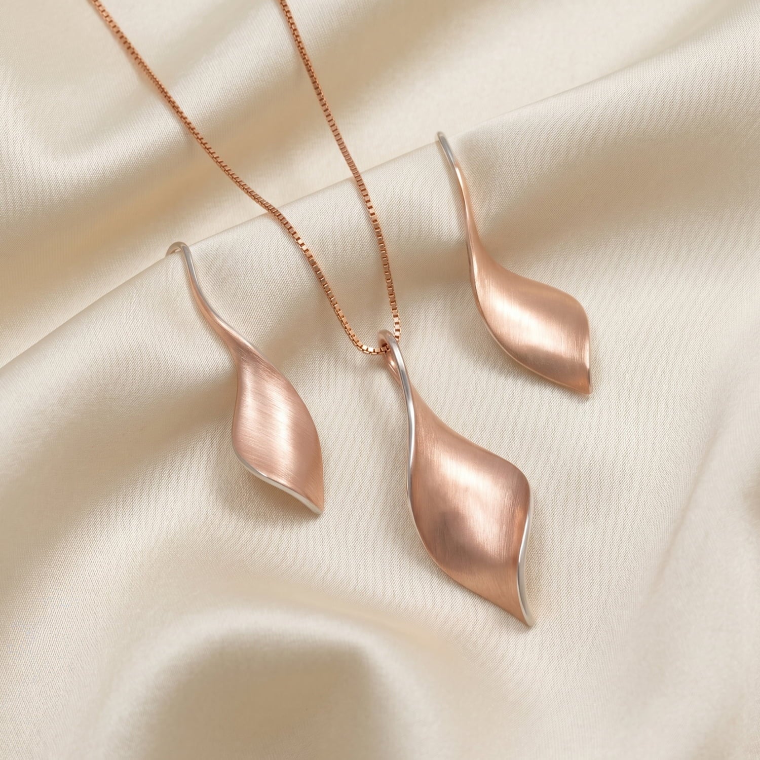 Rose gold vermeil twisting pendant and earring set on cream silk