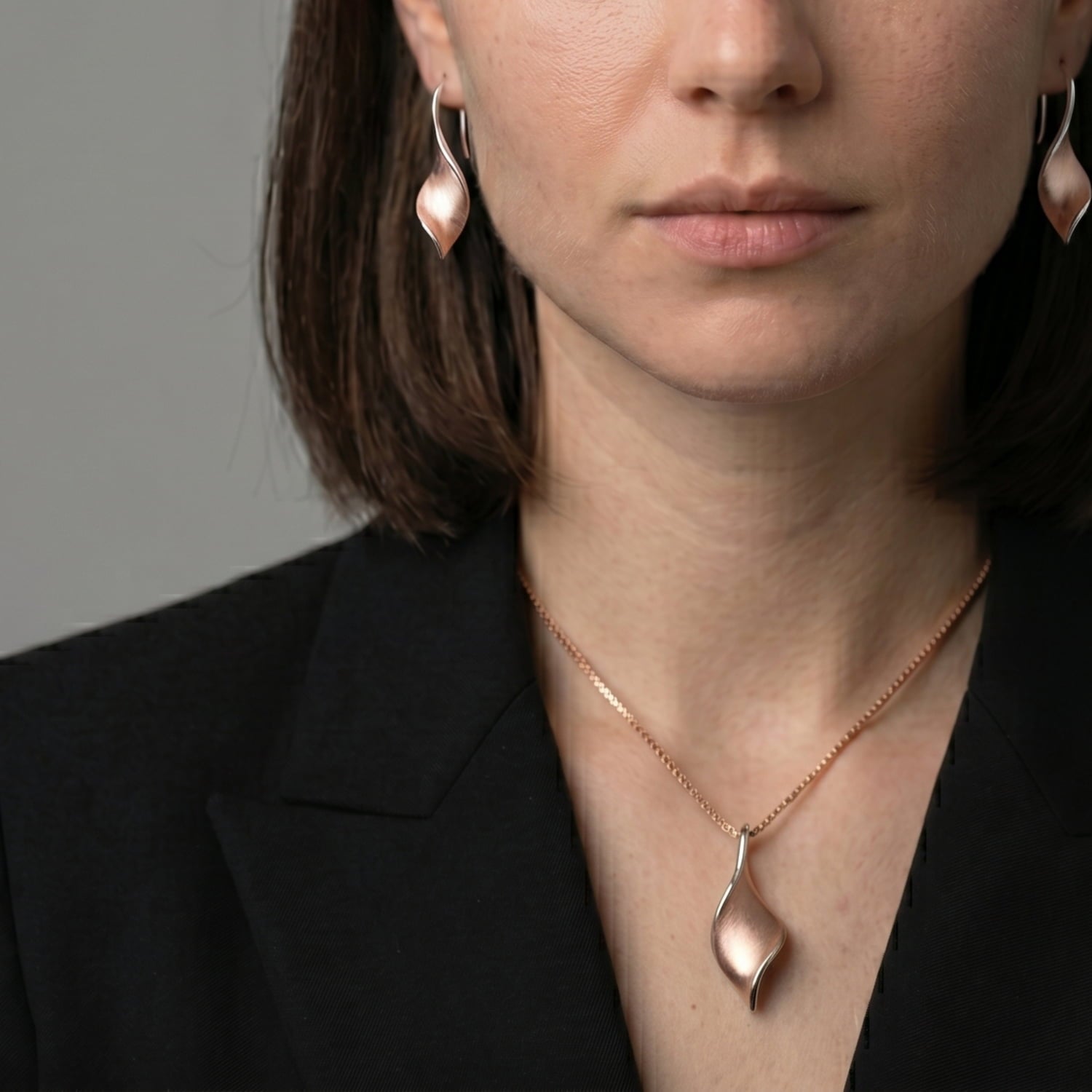 Woman in black blazer wears a rose gold vermeil twist pendant and drop earrings