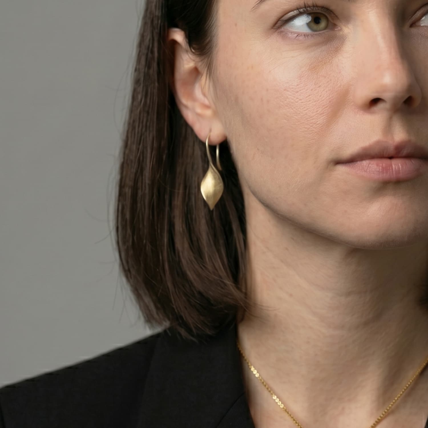 Woman wears twisting yellow gold vermeil drop earrings