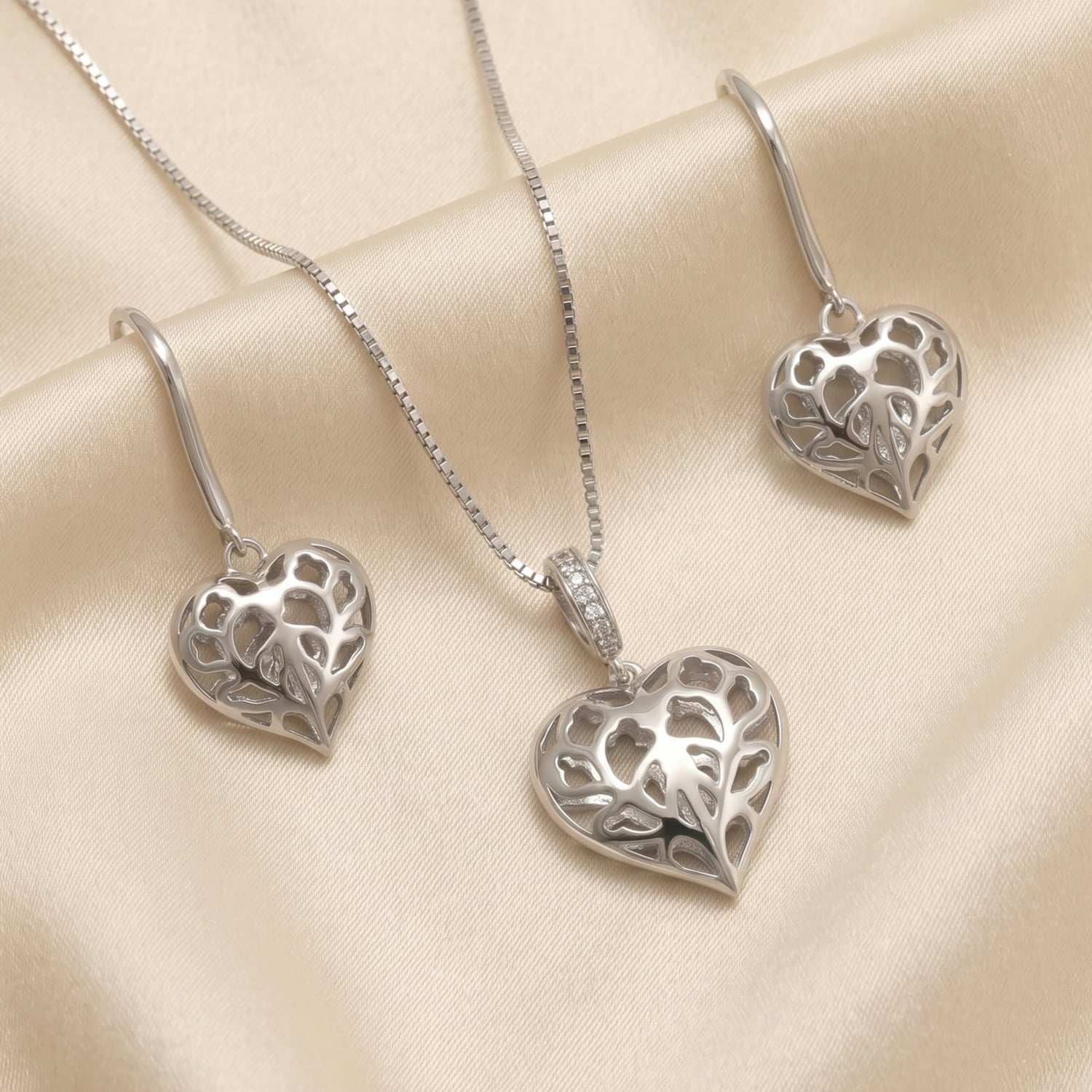 Sterling silver drop earrings and matching pendant featuring delicate openwork hearts with intricate leaf-inspired cut-out patterns on a fine chain.
