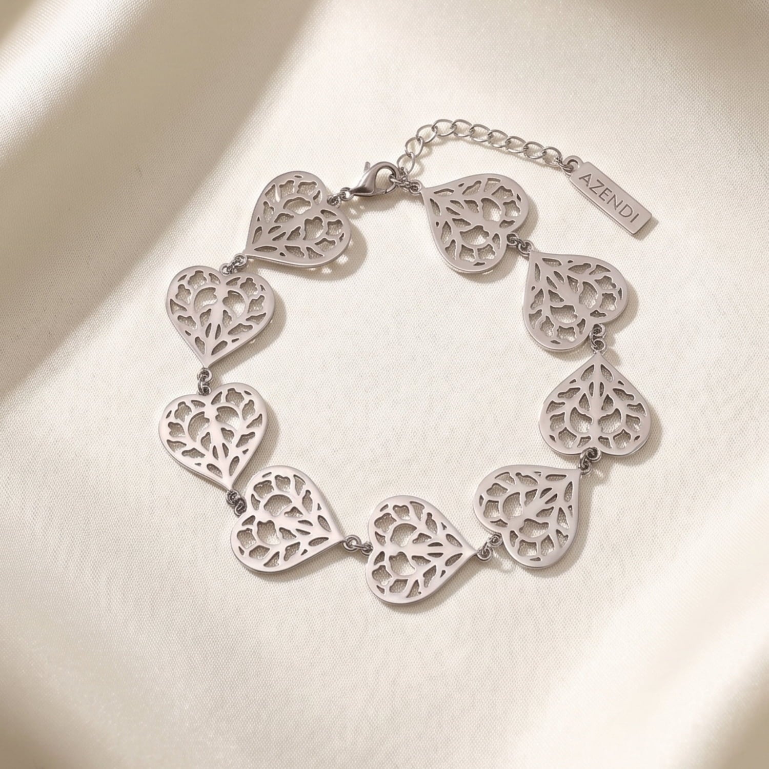 Sterling silver bracelet featuring interconnected openwork heart links with intricate filigree detailing and an adjustable chain, exemplifying elegant British craftsmanship.