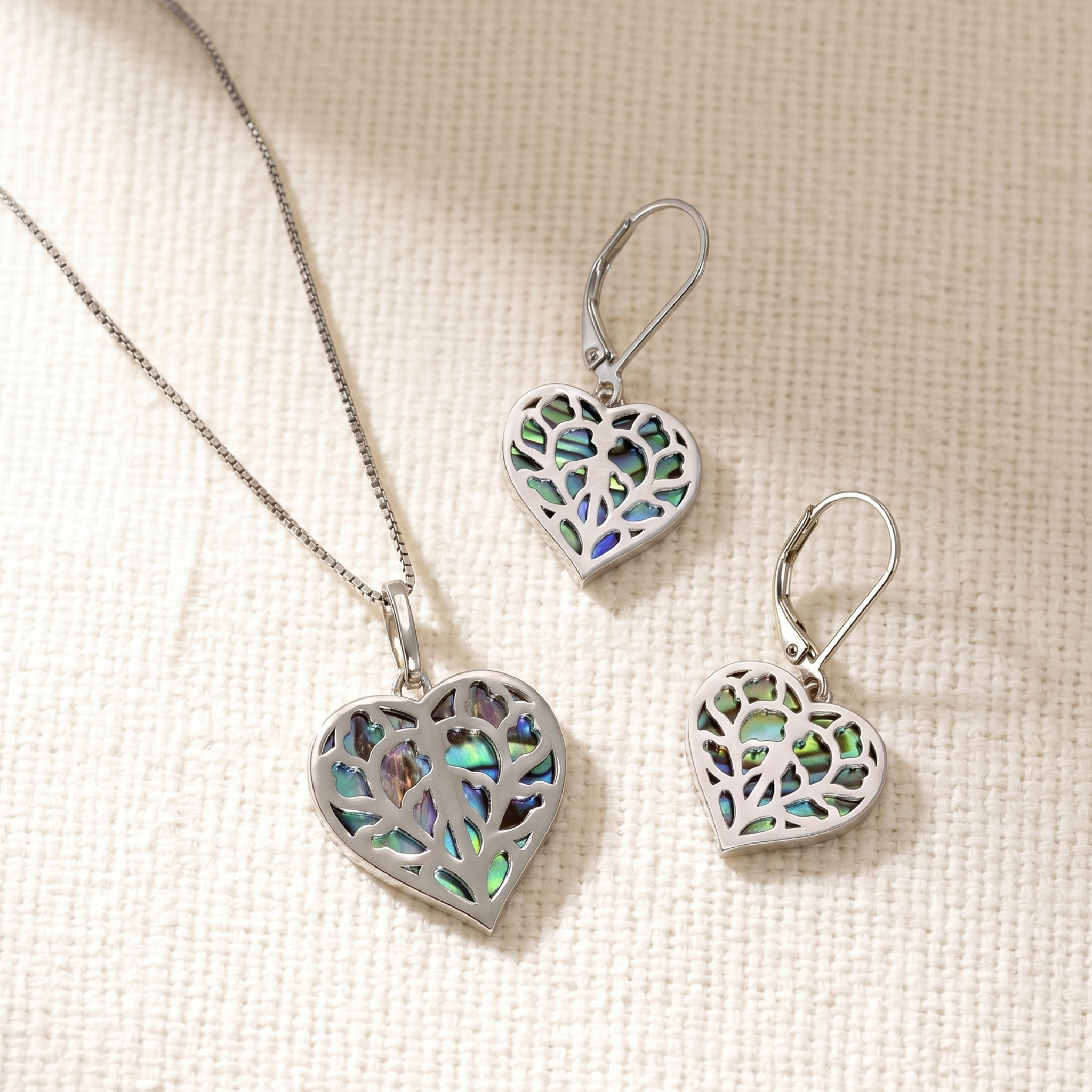 Sterling silver earrings and pendant featuring openwork heart shapes with iridescent abalone inlay, showcasing intricate vine-like detailing.