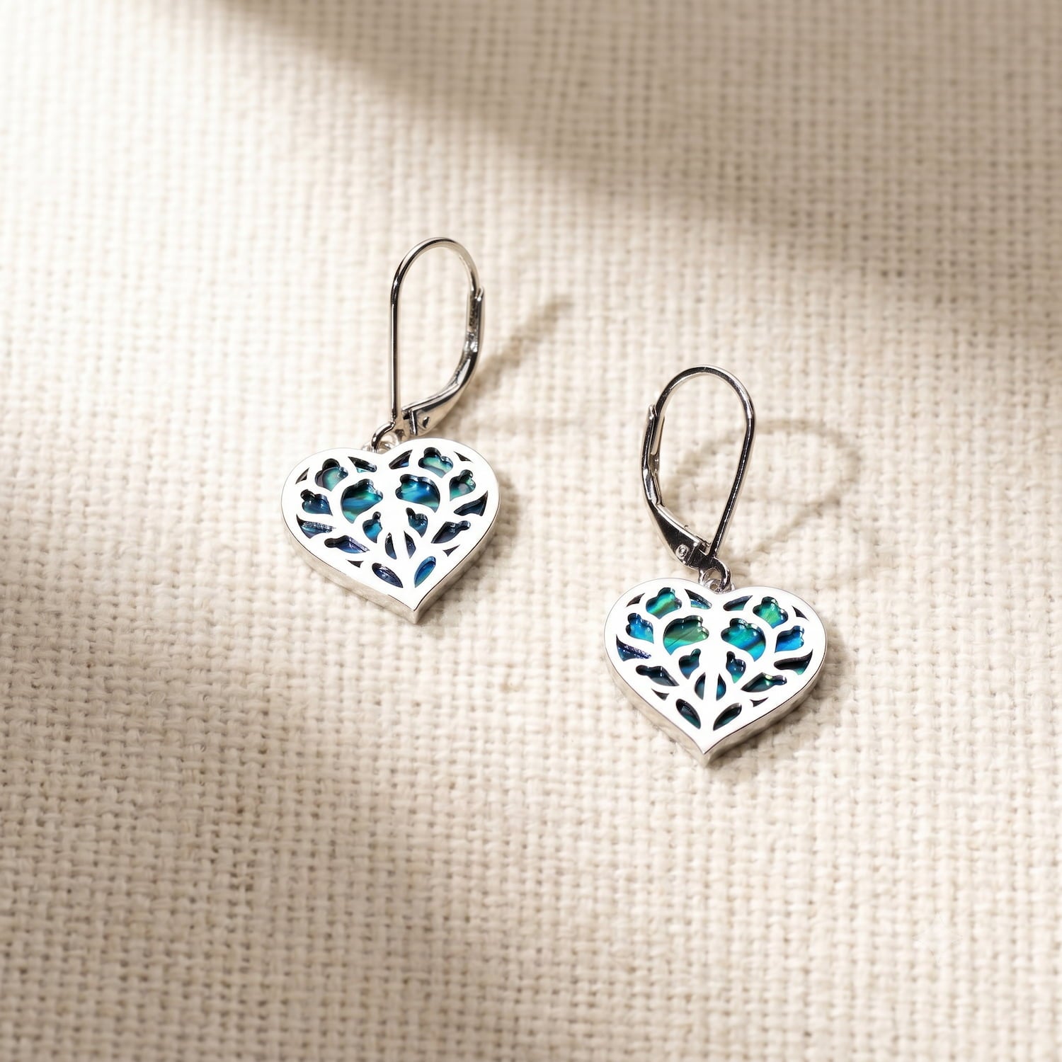 Pair of sterling silver drop earrings featuring heart-shaped abalone inlays with an intricate openwork design, combining contemporary craftsmanship with elegant silver jewellery.