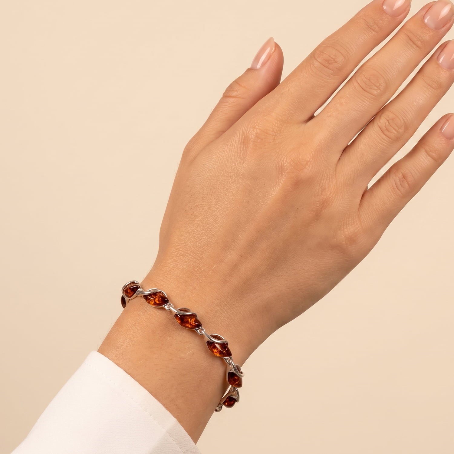 Sterling silver bracelet featuring twisted links with warm amber teardrop stones, displaying a refined and sculptural design on the wrist.