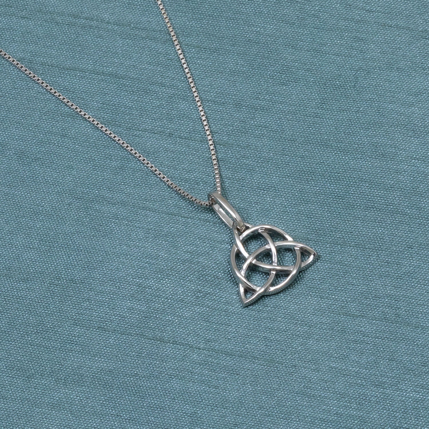 Sterling silver pendant featuring an intricately woven Celtic Trinity knot design suspended from a fine chain, exemplifying elegant and sculptural silver jewellery.