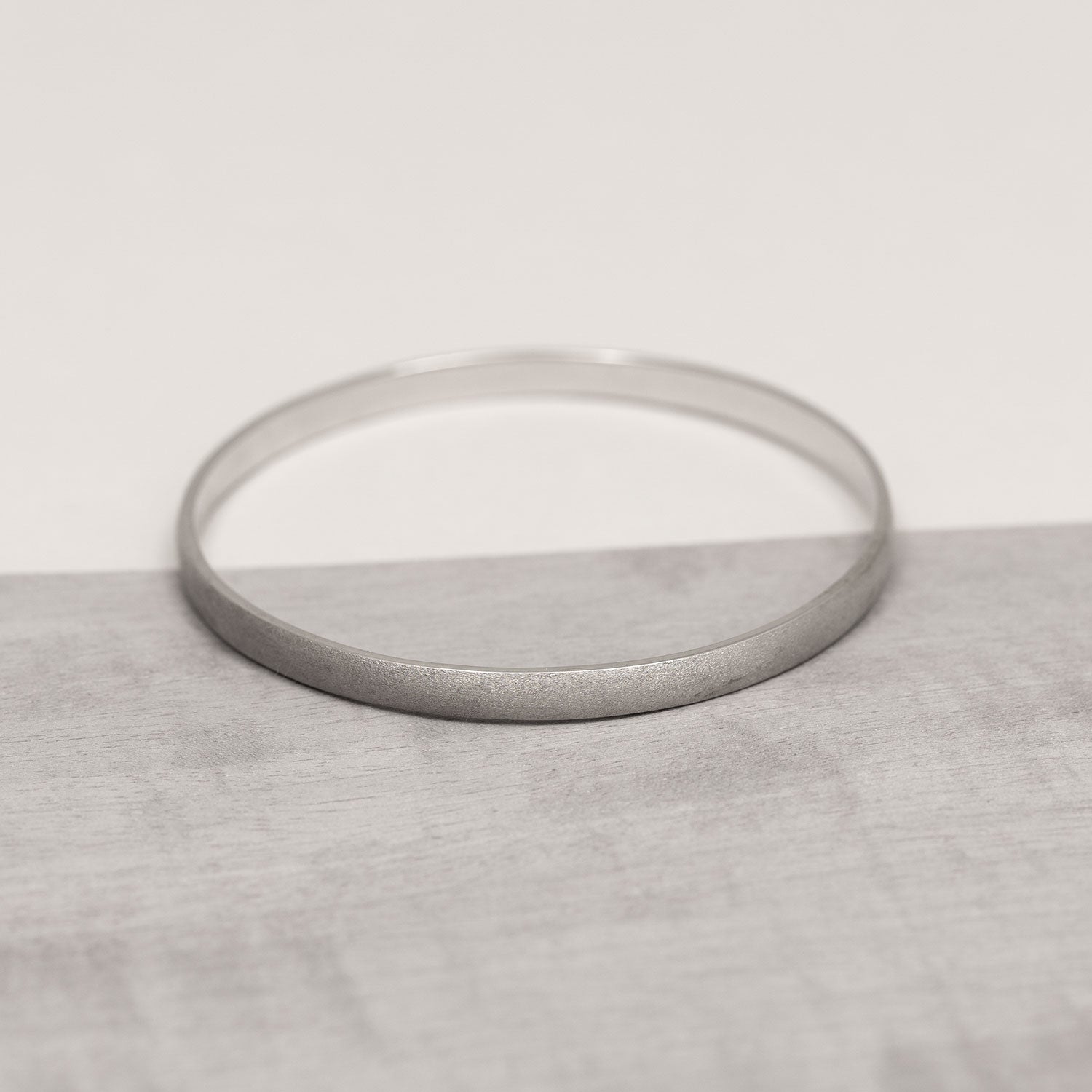 Sterling silver bangle with a satin finish, featuring a smooth, understated design that highlights the elegant simplicity of contemporary silver jewellery.