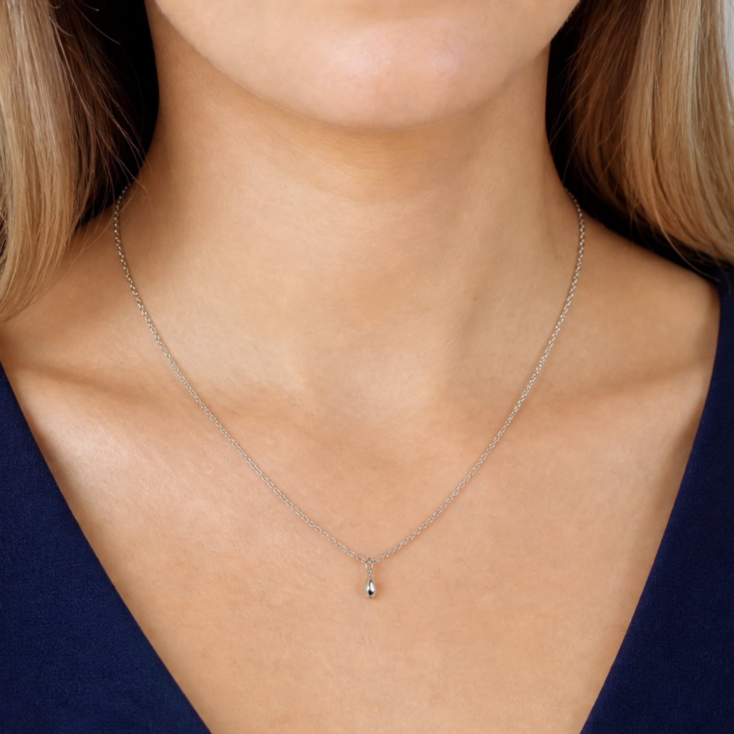 Model wears delicate sterling silver necklace featuring a sculptural raindrop pendant suspended from a fine chain with adjustable length for versatile styling.