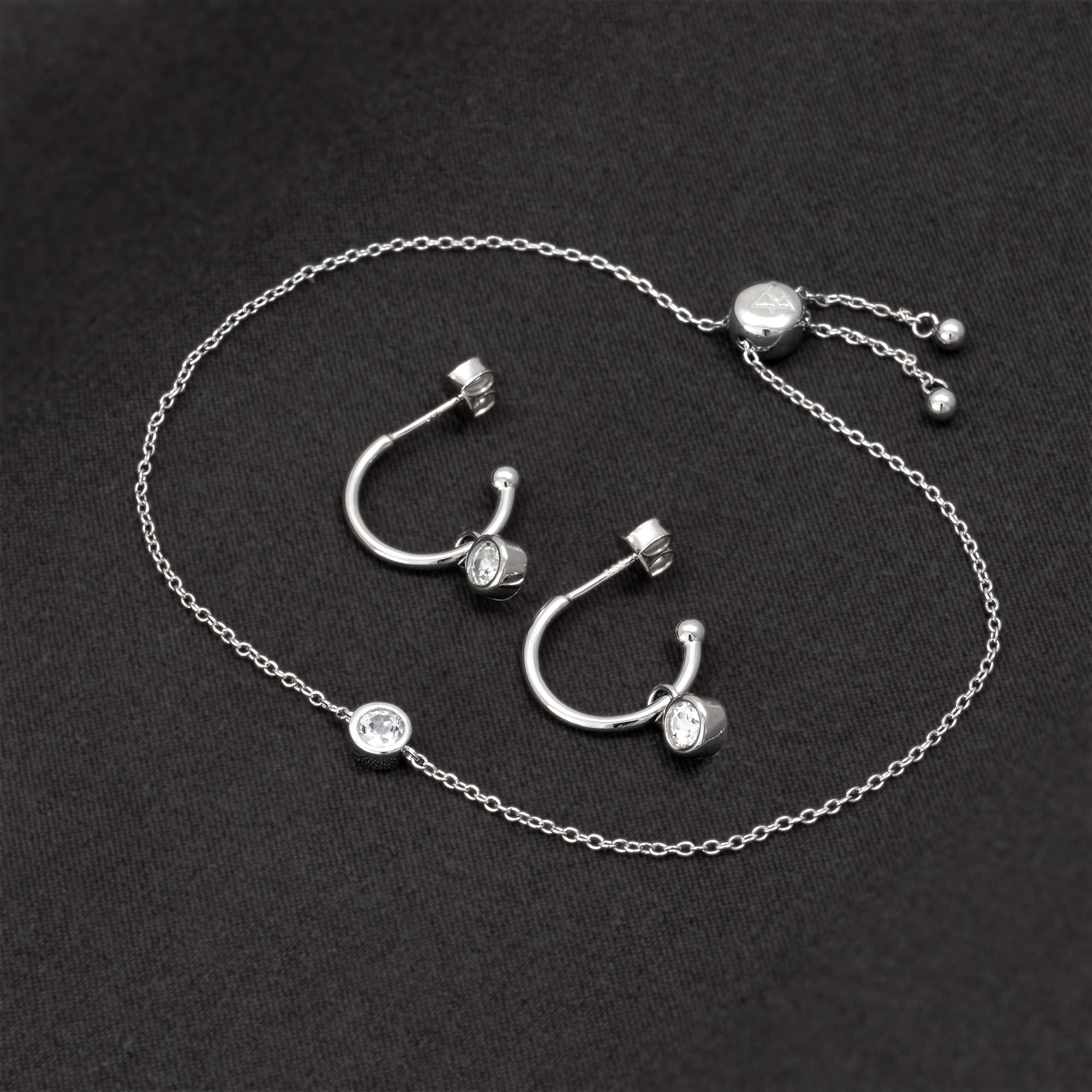 Delicate sterling silver hoops featuring white topaz stones paired with an adjustable sterling silver chain bracelet, embodying refined British craftsmanship.