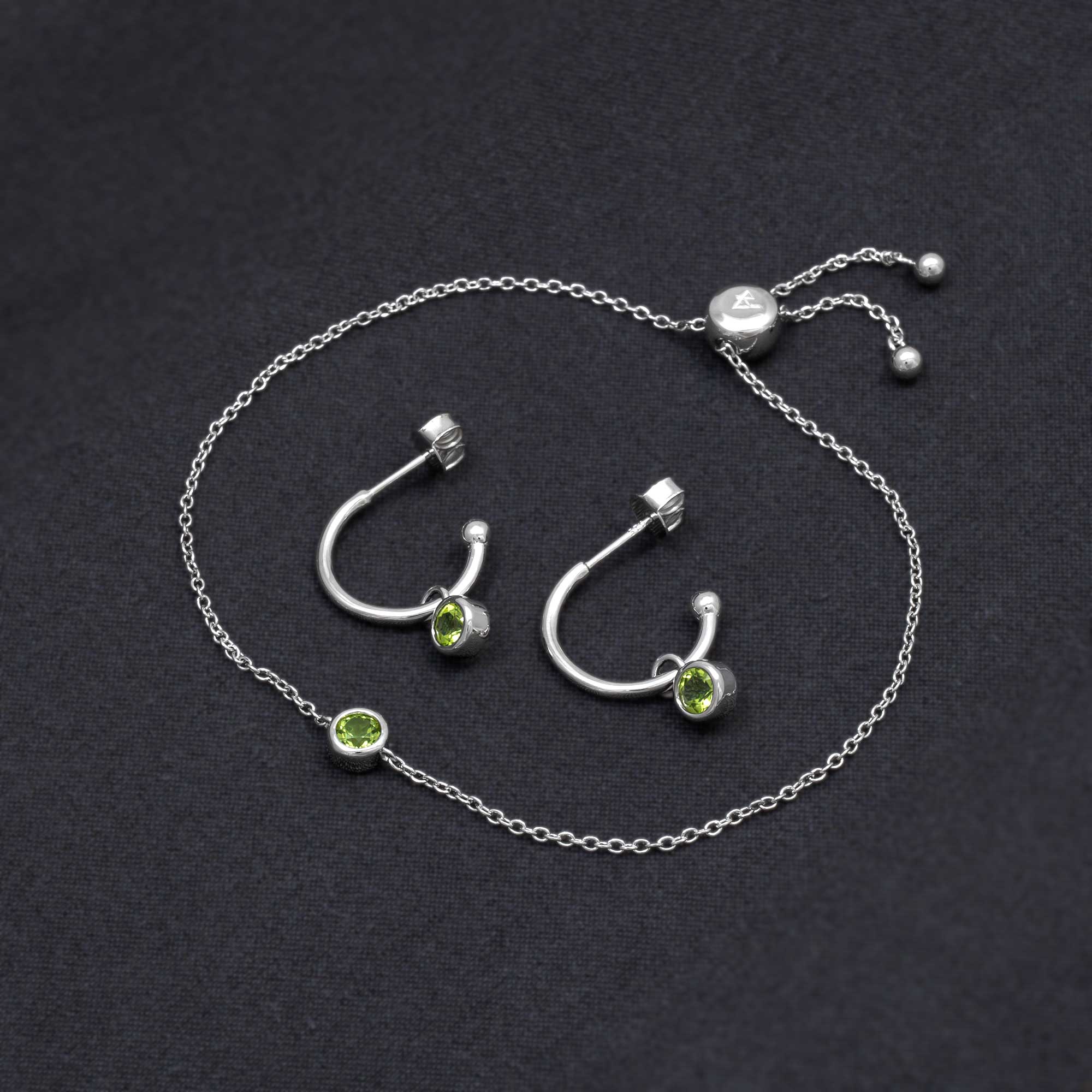 Sterling silver hoop earrings featuring vibrant peridot gemstones paired with a delicate adjustable chain bracelet, showcasing refined British craftsmanship.