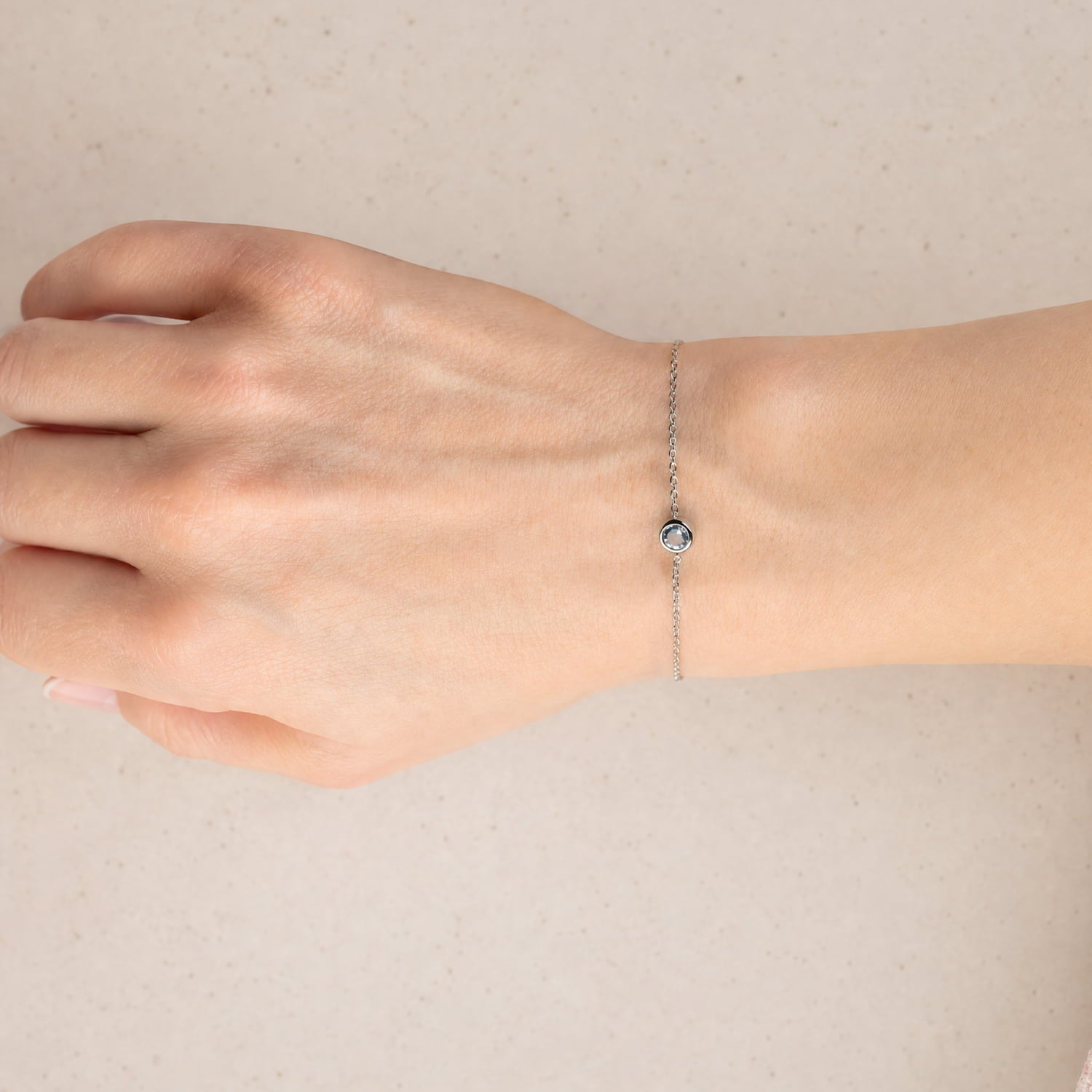 Delicate sterling silver bracelet featuring a blue topaz birthstone set in a minimalist bezel on a fine adjustable chain, exemplifying refined British design.