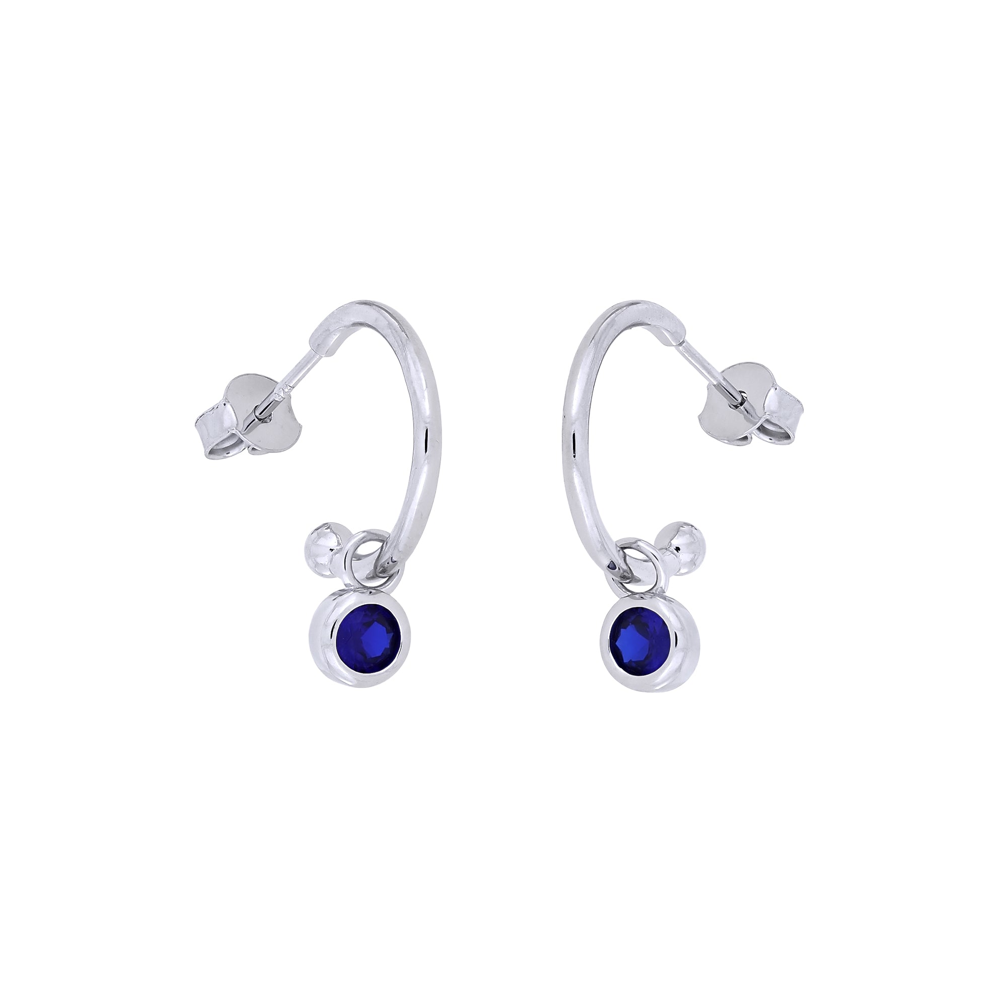 Delicate sterling silver hoops featuring deep blue spinel gemstones, designed as elegant birthstone earrings with a minimalist, contemporary aesthetic.