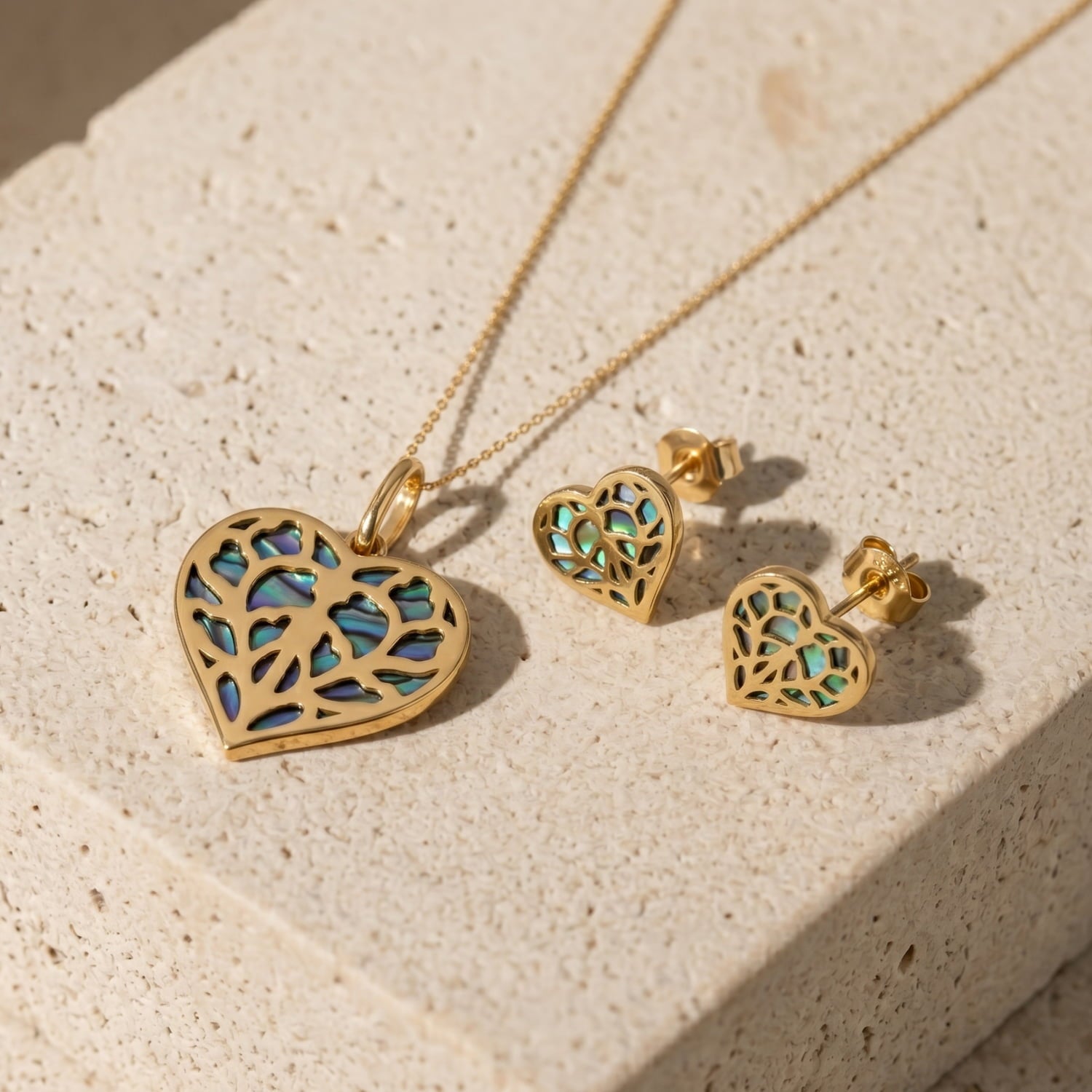 9 carat yellow gold pendant and earrings in a heart shape featuring intricate openwork with iridescent abalone inlay