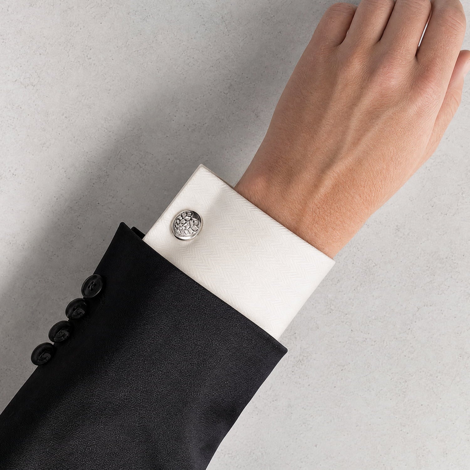 Round sterling silver cufflinks featuring a sculptural Heart of Yorkshire design, styled on a white shirt cuff paired with a formal black jacket.