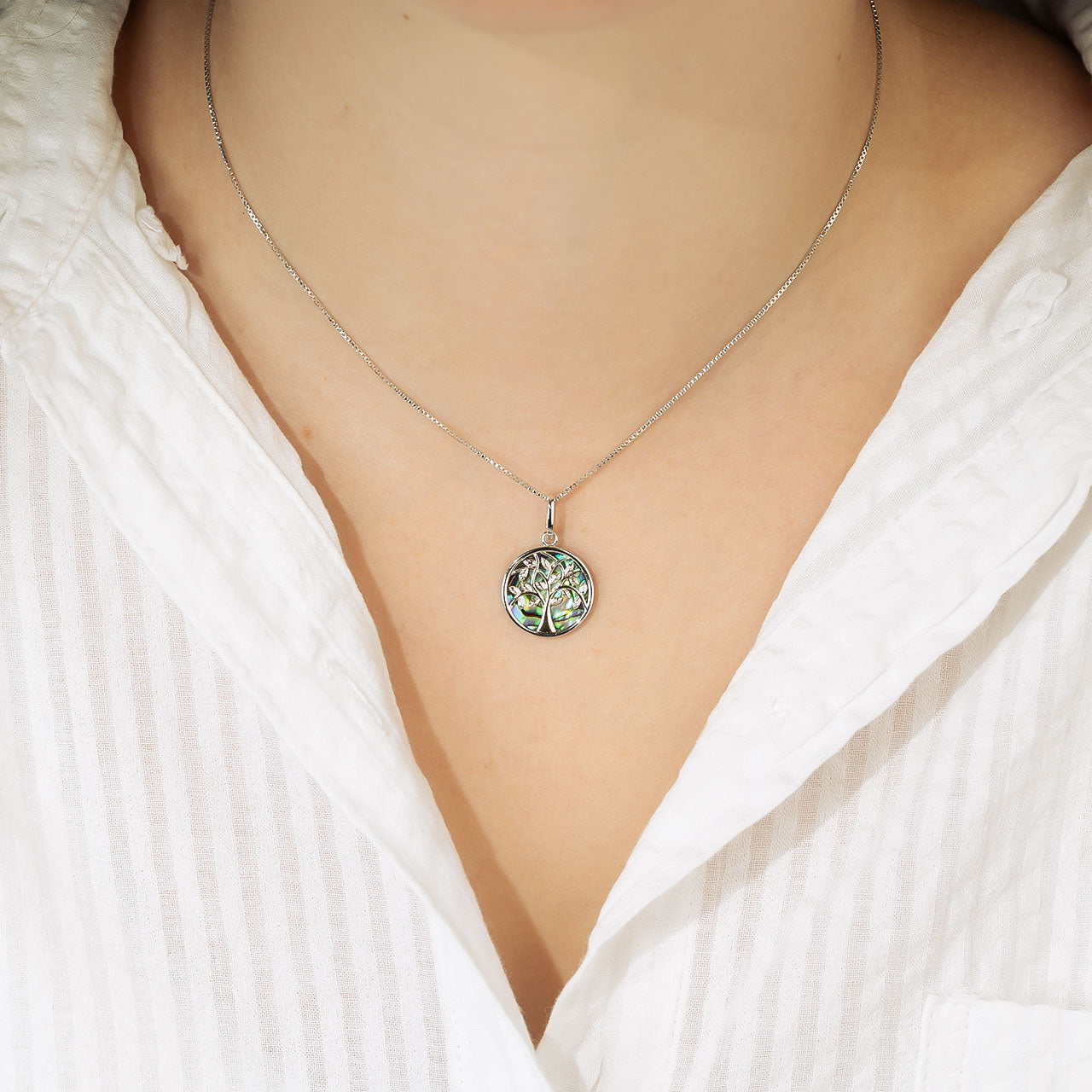 Sterling silver pendant featuring a sculptural tree of life design with iridescent abalone inlay, suspended on a fine chain for a contemporary silver jewellery statement.