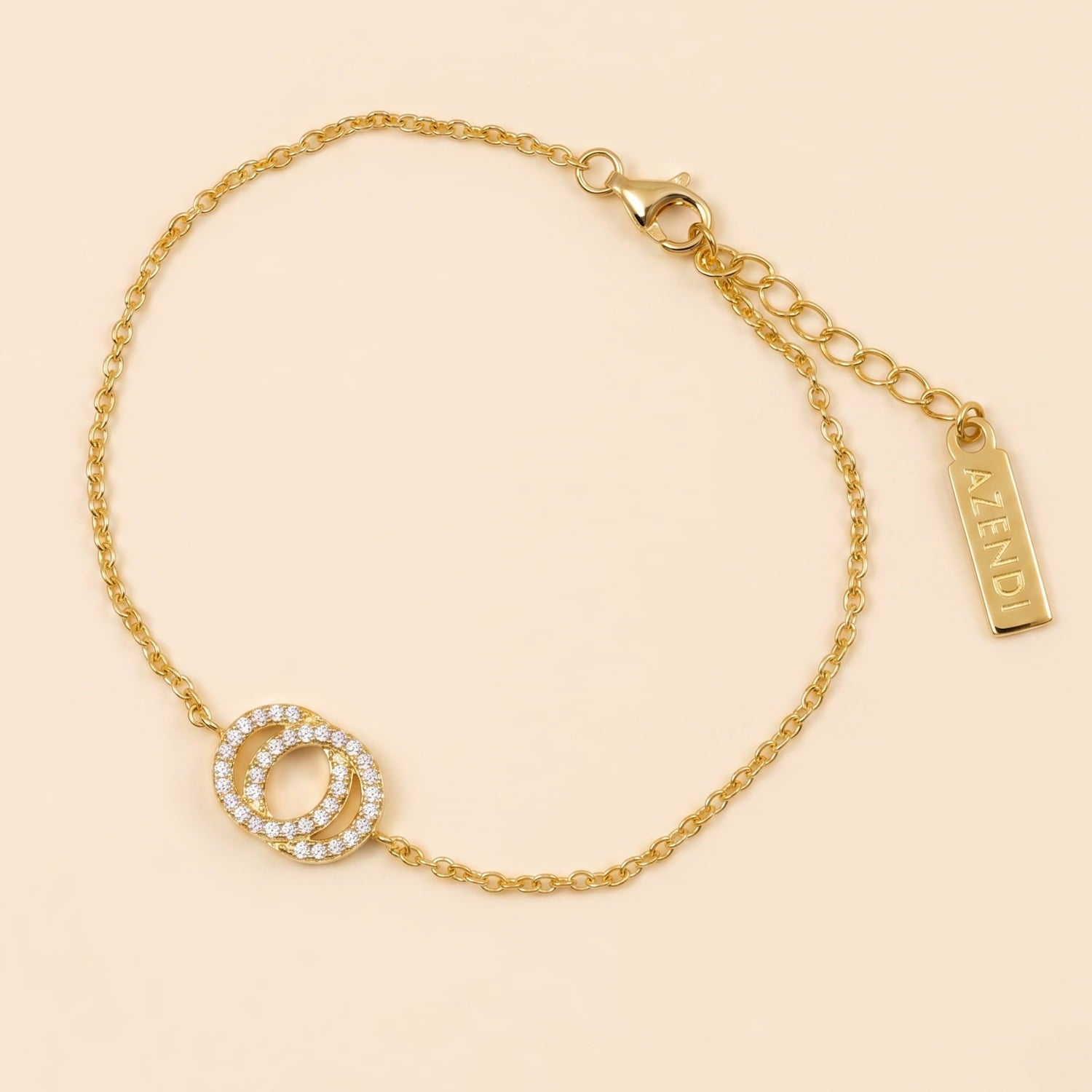 Delicate gold vermeil bracelet featuring interlocking circles embellished with sparkling cubic zirconia, adjustable chain, and a branded Azendi tag on a plain cream background.