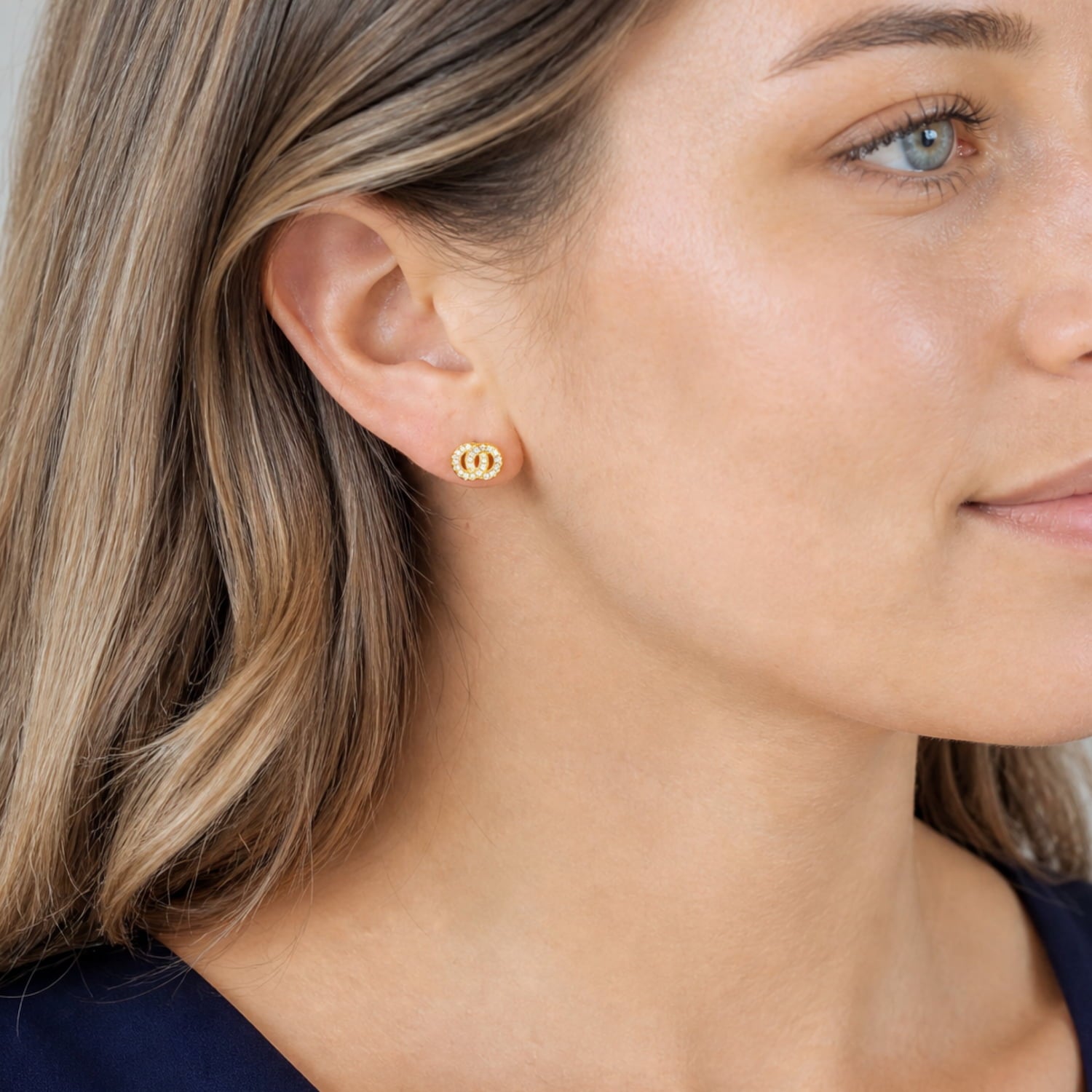 Pair of yellow gold vermeil stud earrings featuring interlocking circles accented with sparkling cubic zirconia, styled on the ear for a refined and elegant look.