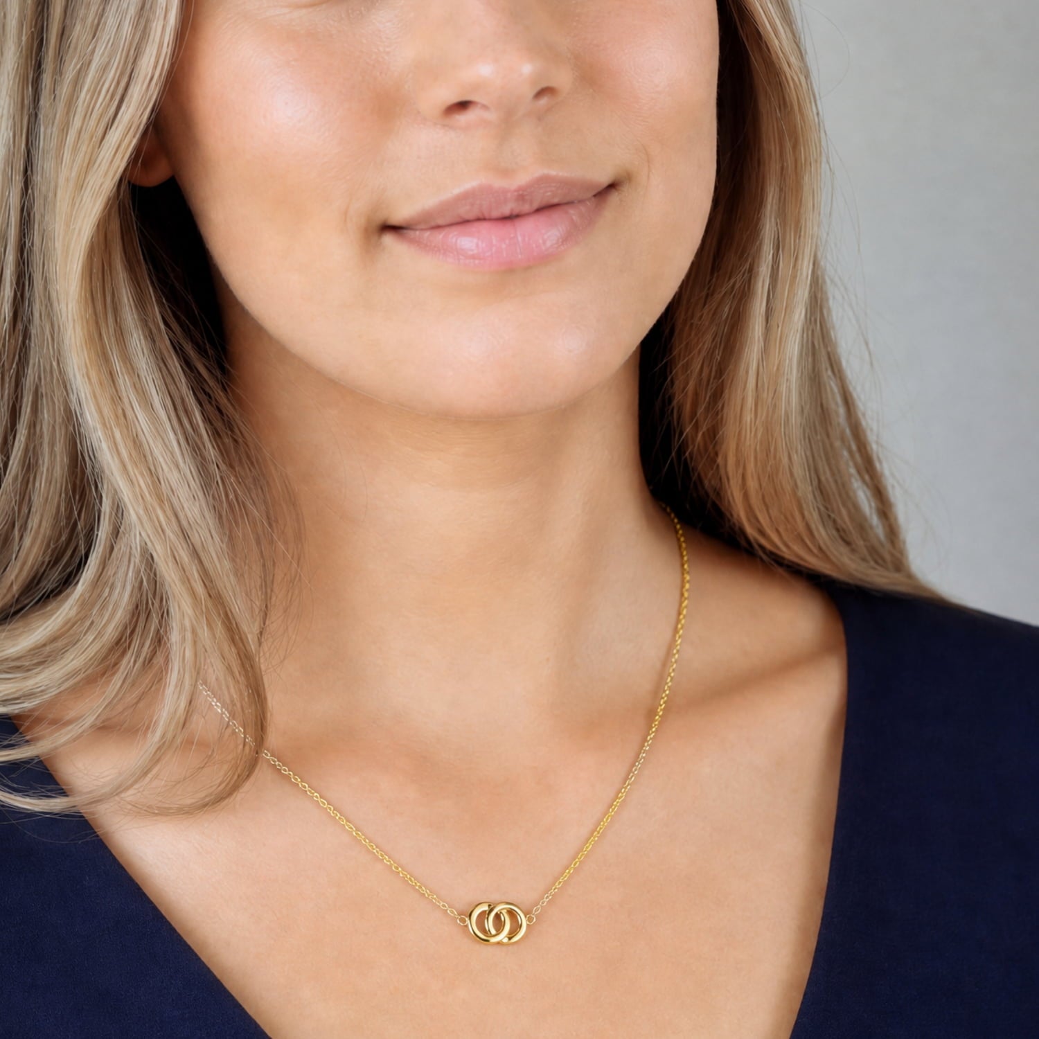 Delicate yellow gold vermeil necklace featuring two interlocking circles on an adjustable fine chain, styled with a crisp white shirt for a refined look.