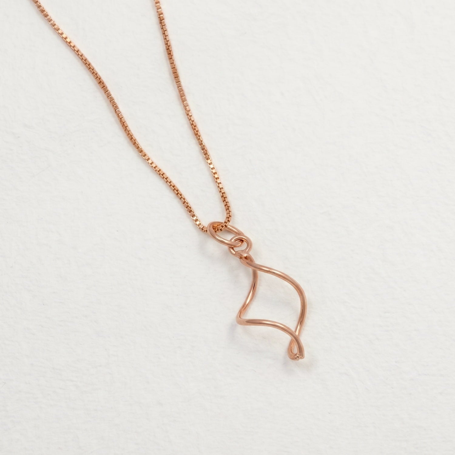 Rose gold vermeil necklace featuring an elegant, sculptural twist pendant suspended from a delicate chain, embodying a modern and refined silver jewellery design.