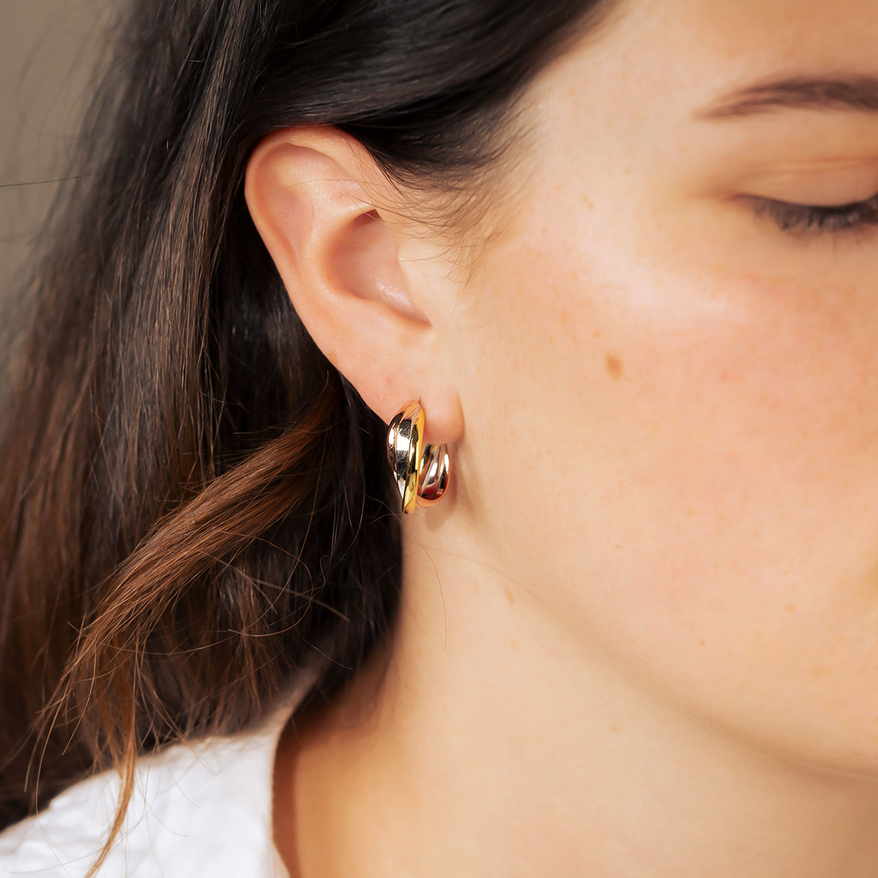 Three-strand hoop earrings featuring intertwined silver, rose gold, and yellow gold finishes, creating a sculptural and polished design in contemporary sterling silver jewellery.
