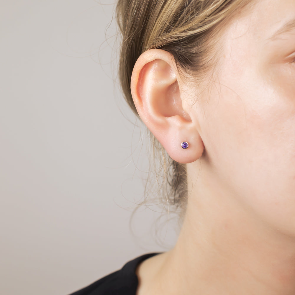 Pair of sterling silver stud earrings featuring 3mm dark violet brilliant cut stones, offering a refined and elegant touch to minimalist silver jewellery collections.