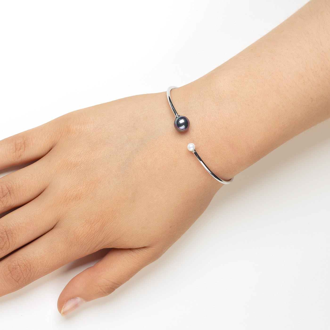 Open-ended sterling silver cuff bangle featuring a flexible band accented with contrasting black and white shell pearls, showcasing elegant British silver jewellery design.