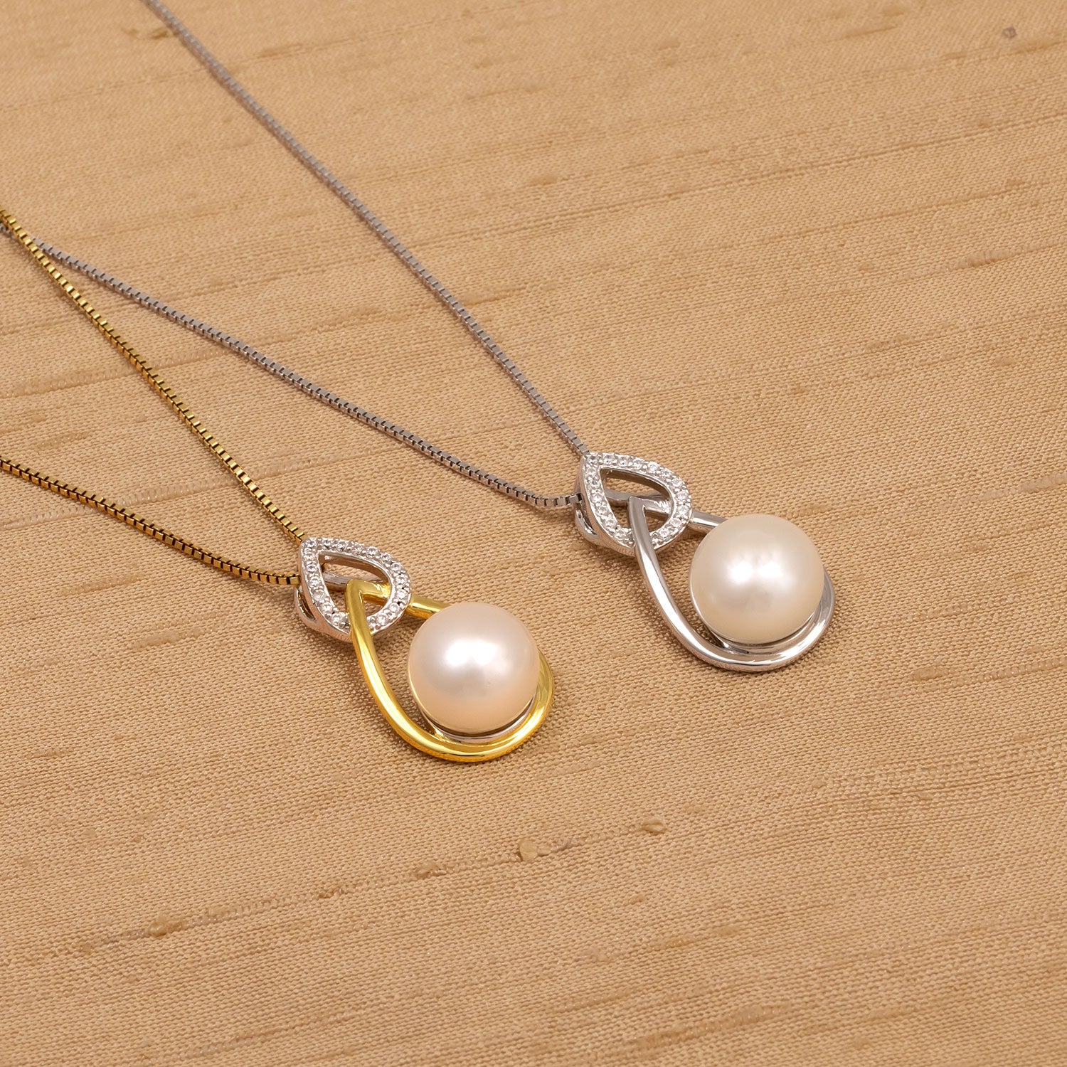 Two elegant teardrop-shaped pendants featuring large freshwater pearls, one in sterling silver and the other in gold vermeil, each accented with small sparkling stones on fine chains.