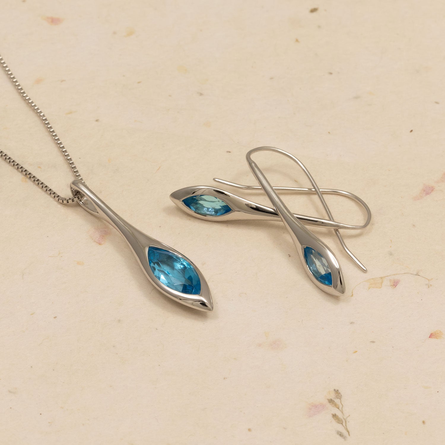 Silver jewelry set with blue gemstones on a beige background